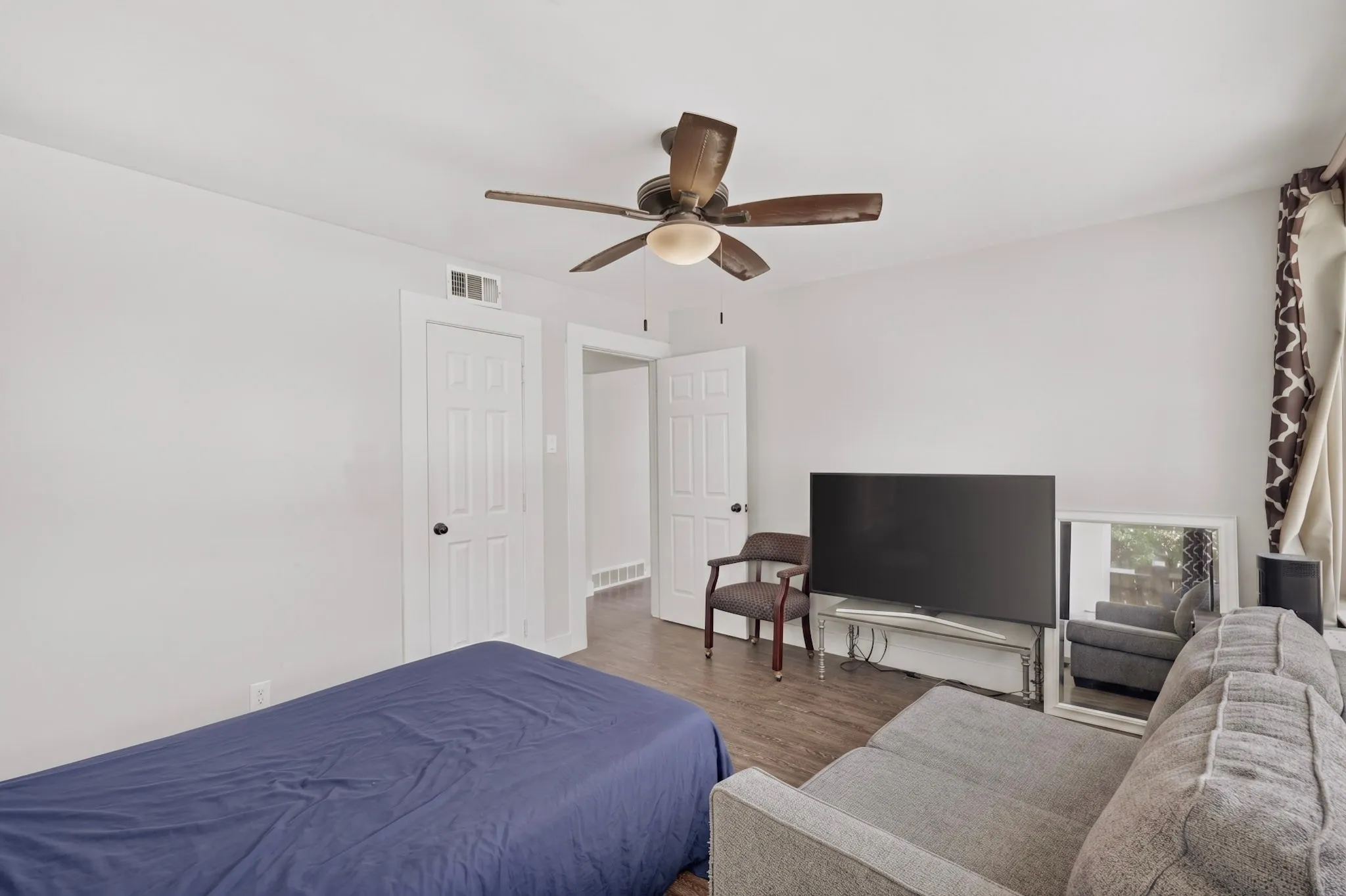 Room featuring wood-finish flooring, white walls, and a ceiling fan with integrated lighting