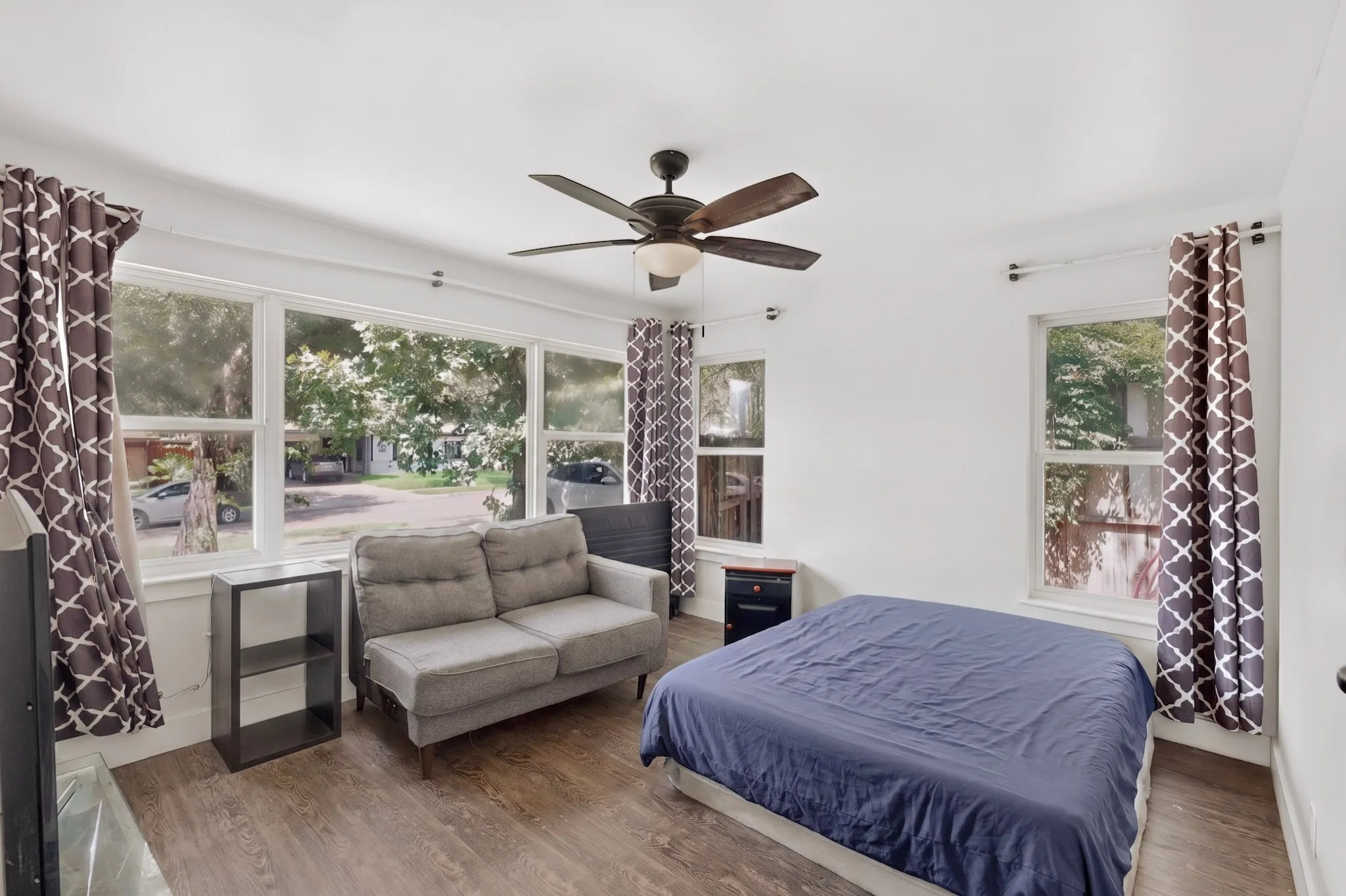 Bright room featuring wood-finish flooring and a ceiling fan with integrated lighting