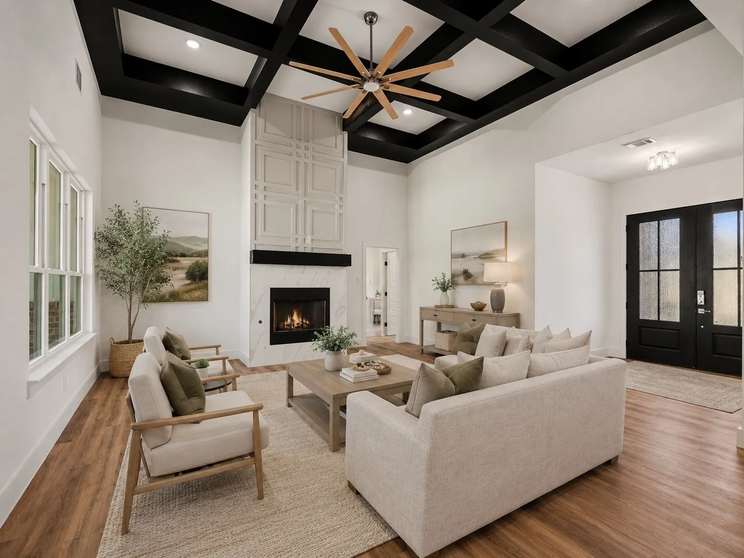 Spacious living area featuring a coffered ceiling with a wood-blade fan, a fireplace with a marble-finish surround, and a decorative paneled accent wall