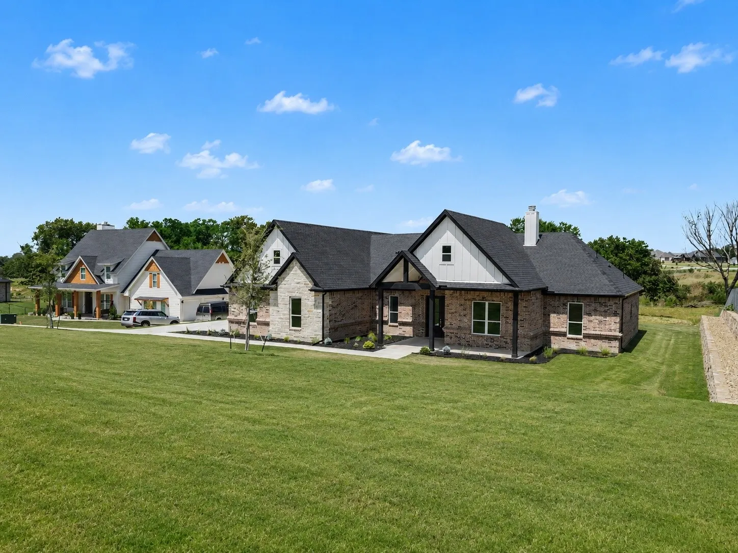 Contemporary ranch-style home featuring a brick and stone facade with dark trim accents