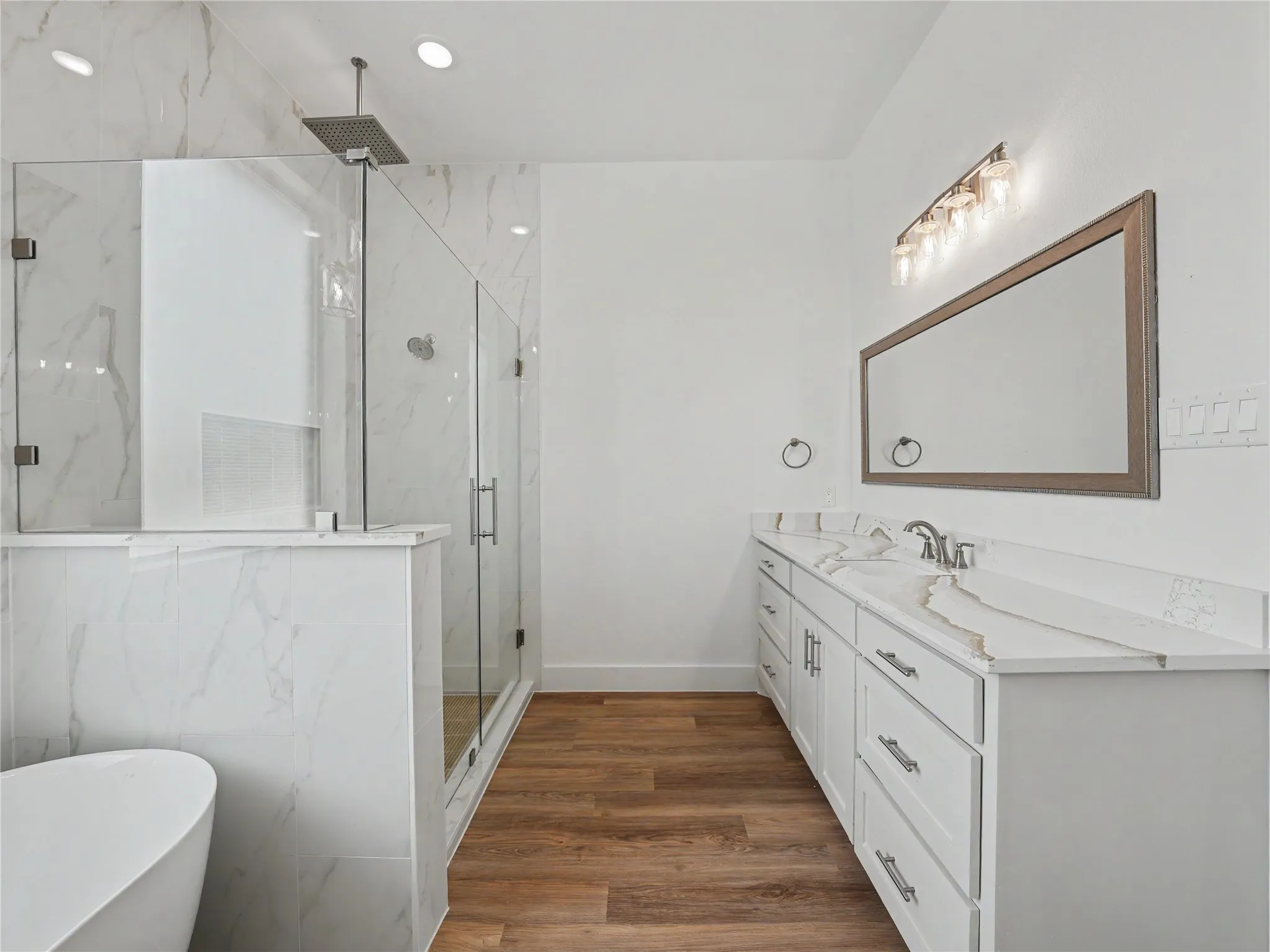 Modern bathroom featuring a glass-enclosed shower with rain showerhead, freestanding soaking tub, and double vanity with dual sinks