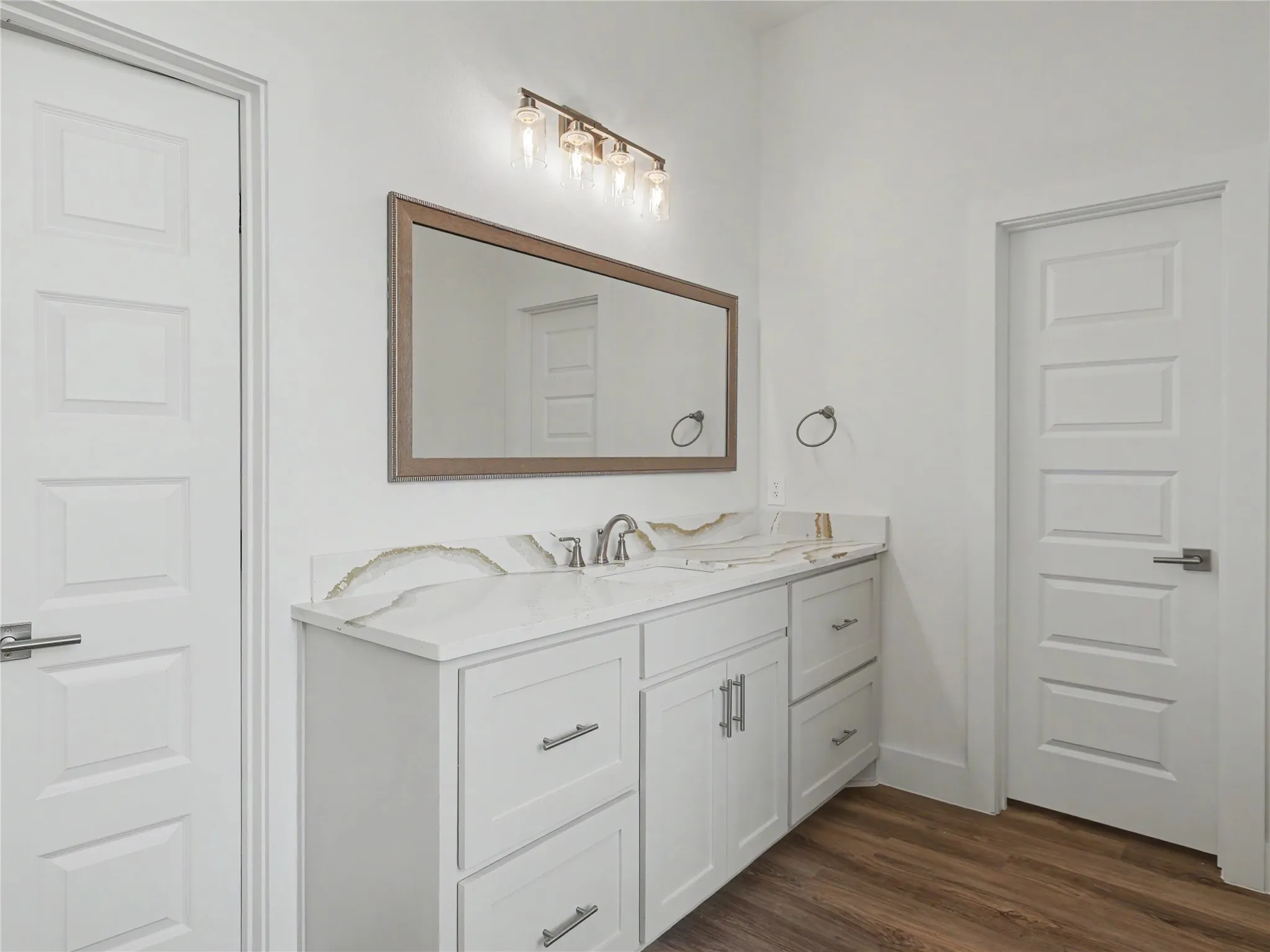 Contemporary vanity featuring a dual-sink countertop with an integrated backsplash, shaker-style cabinetry, and brushed nickel hardware