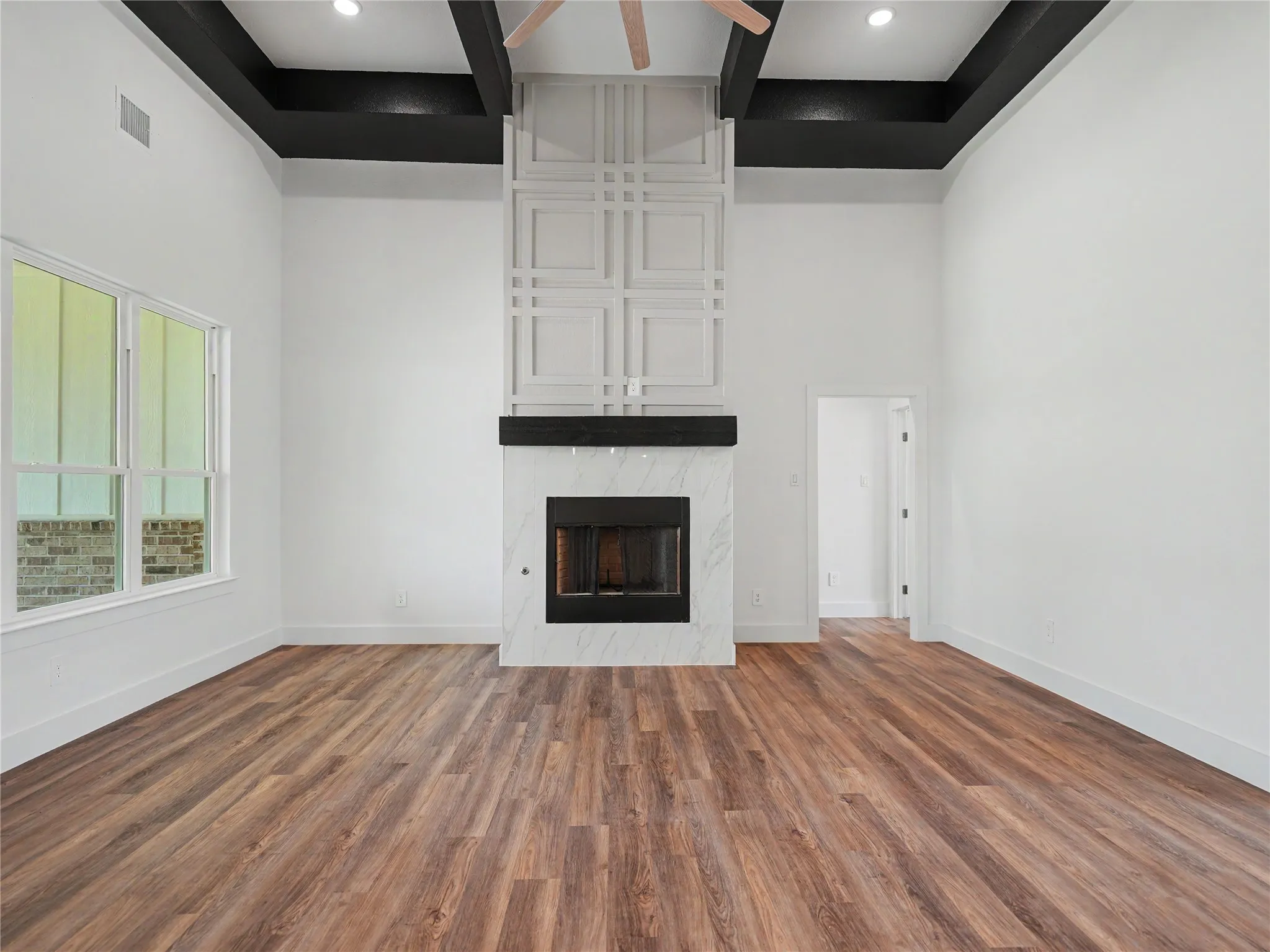 Spacious interior featuring high ceilings with dark contrasting beams and recessed lighting