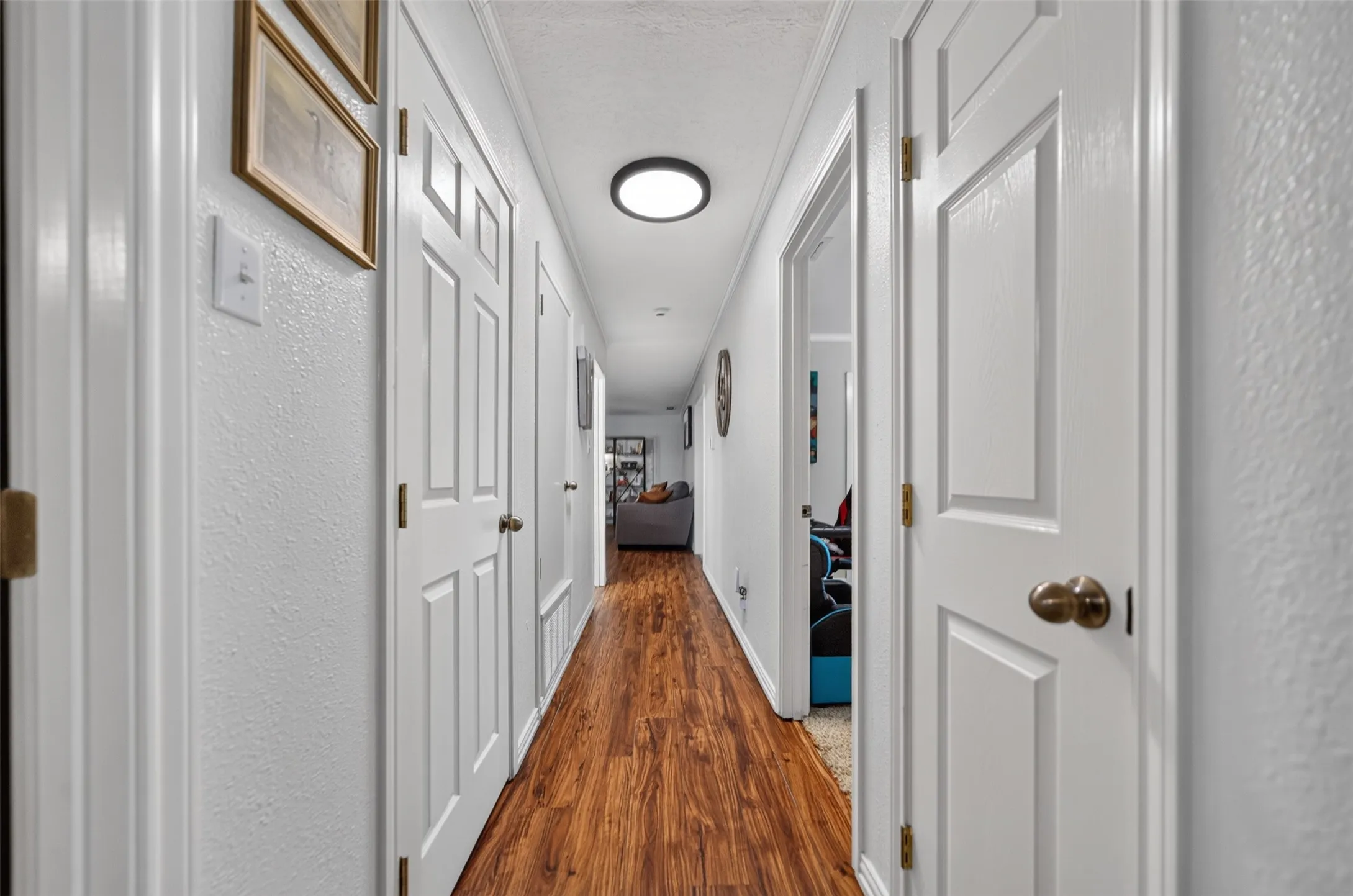 Hallway featuring wood-finish flooring and multiple white paneled doors