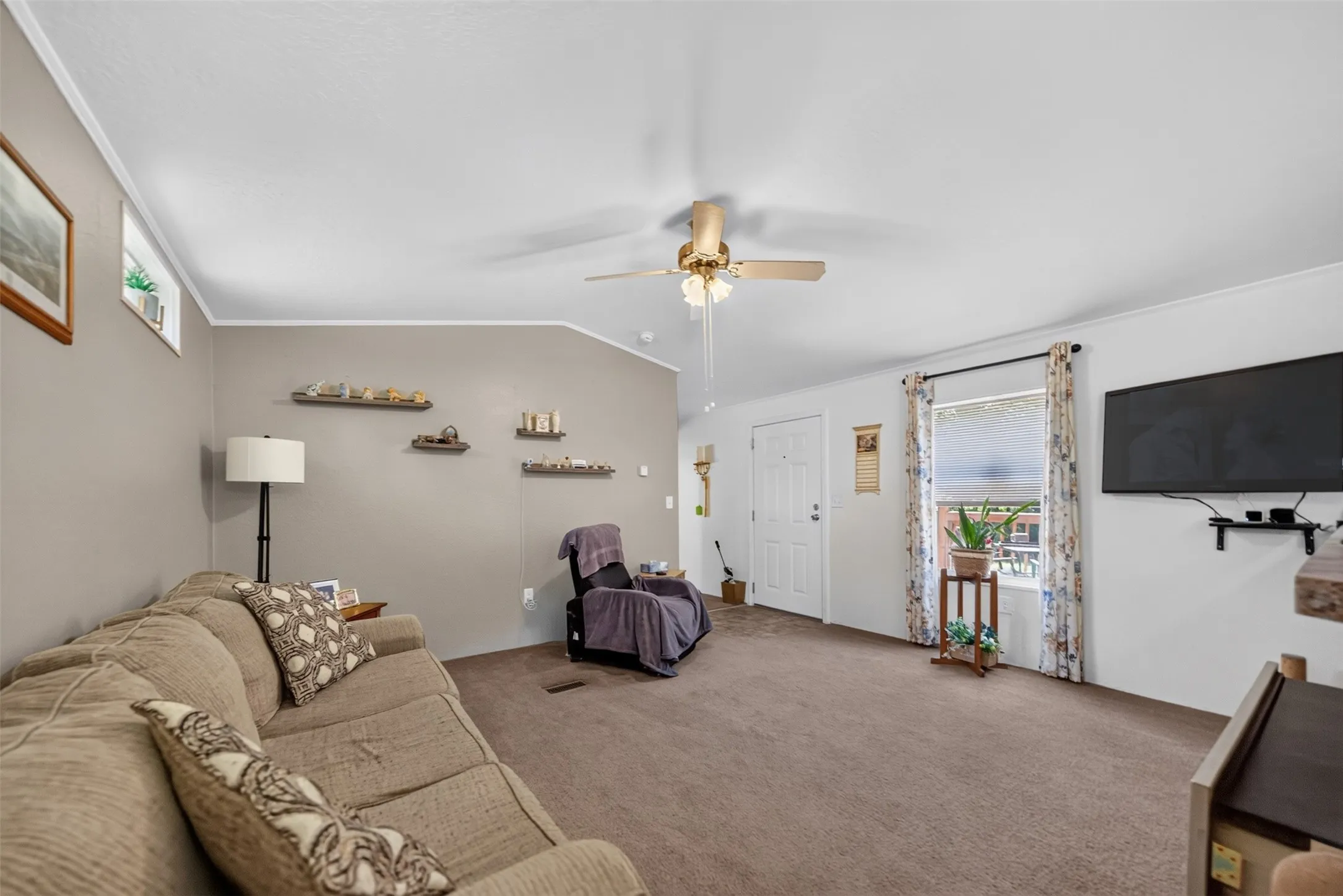 Carpeted living area featuring a ceiling fan, white trim, and a window with blinds