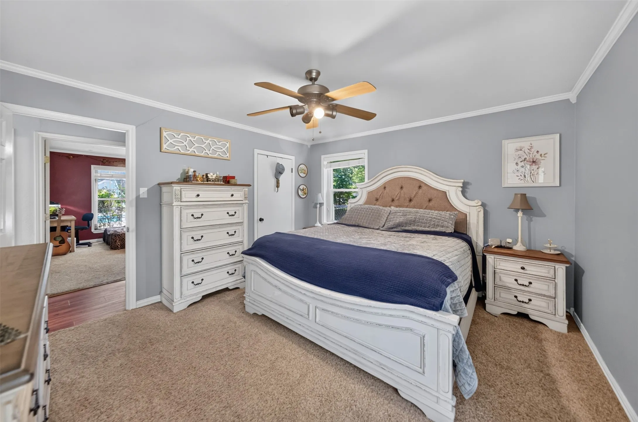 Carpeted bedroom featuring light gray walls, white crown molding, and a ceiling fan with light fixture