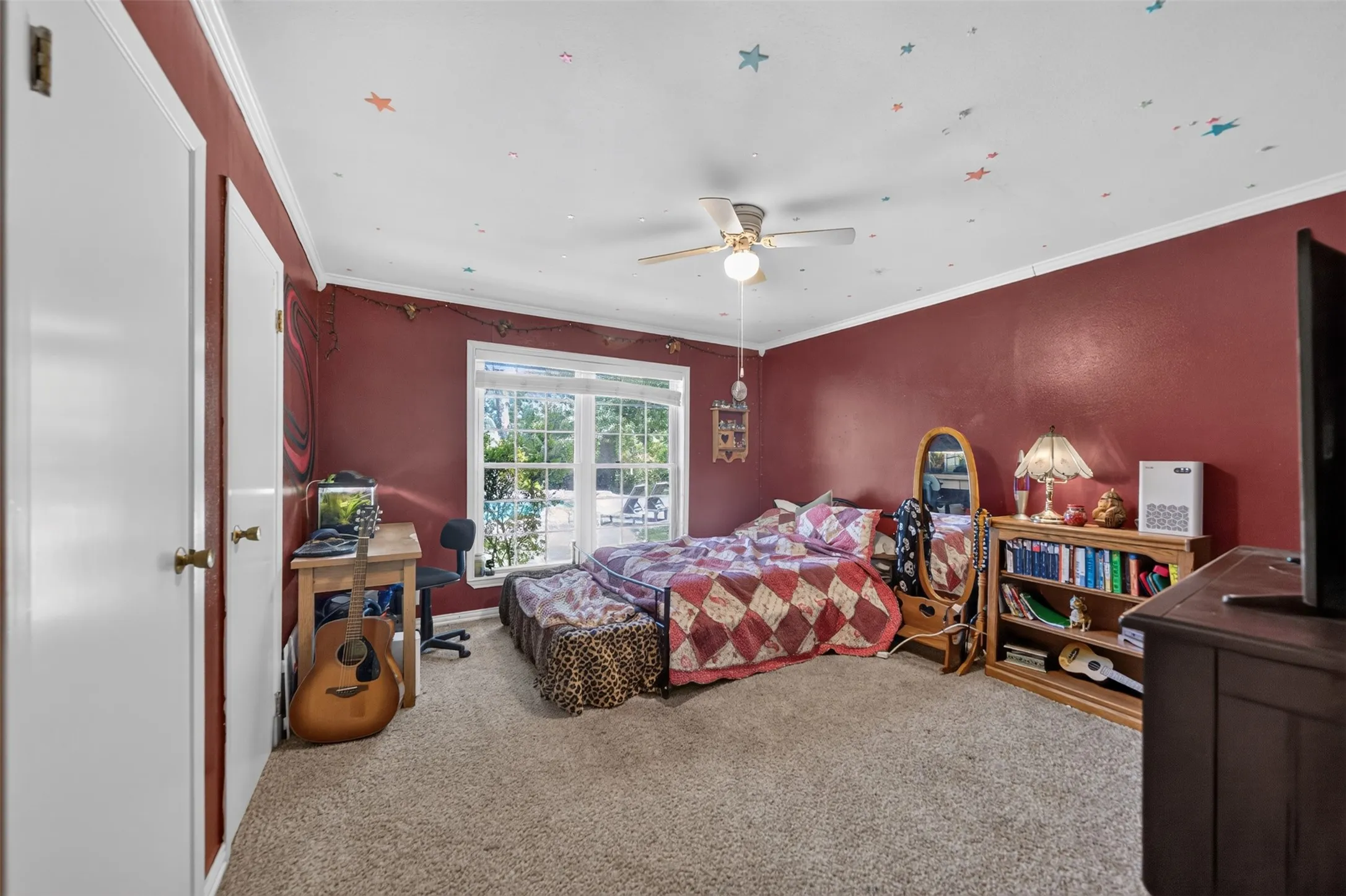 Carpeted room featuring a ceiling fan, crown molding, and two white doors