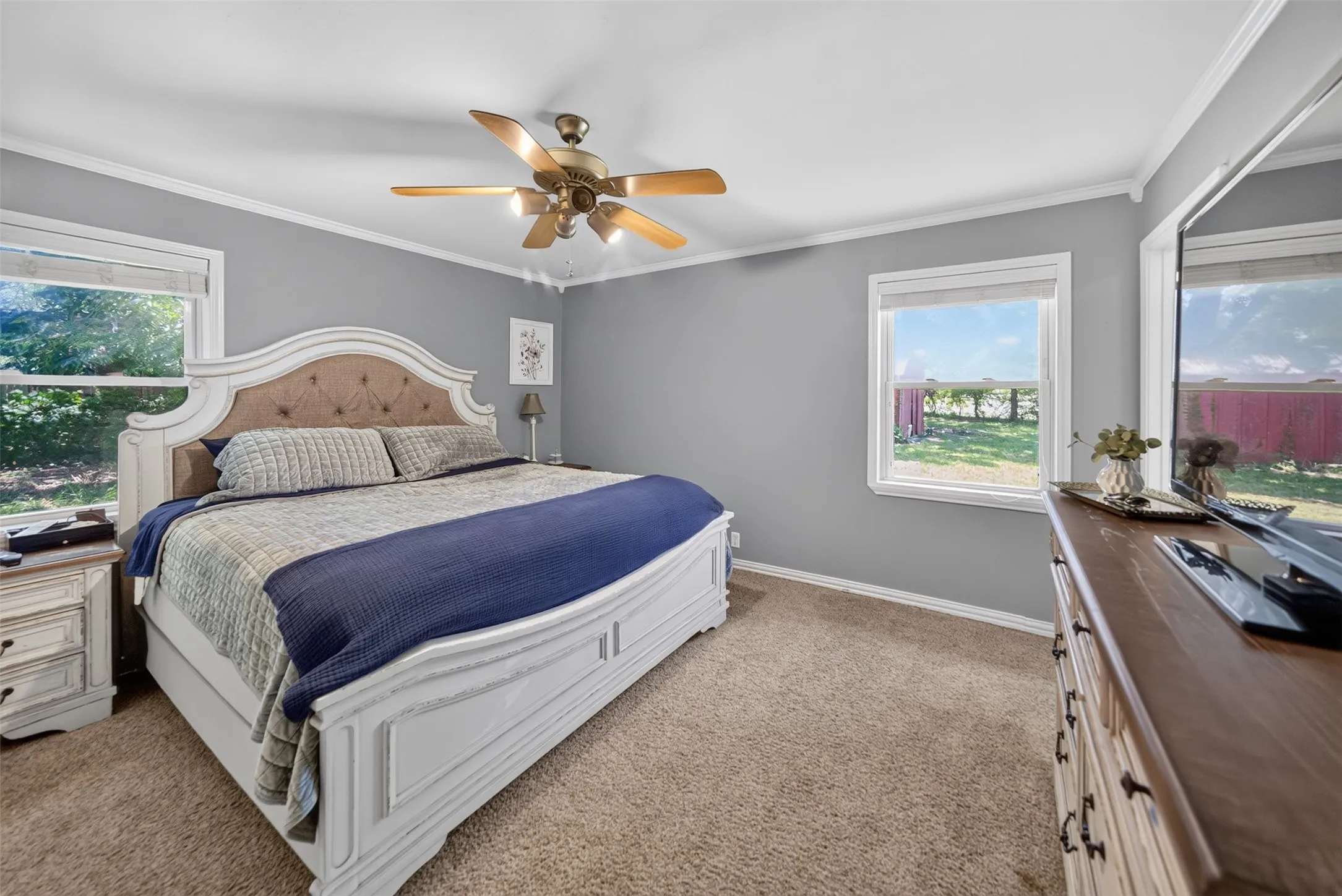 Spacious room featuring neutral carpeting, two windows, and crown molding