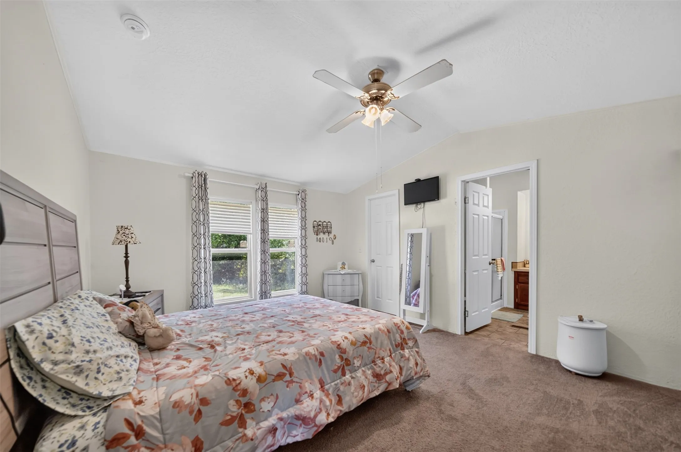 Carpeted bedroom featuring a vaulted ceiling and two windows with blinds