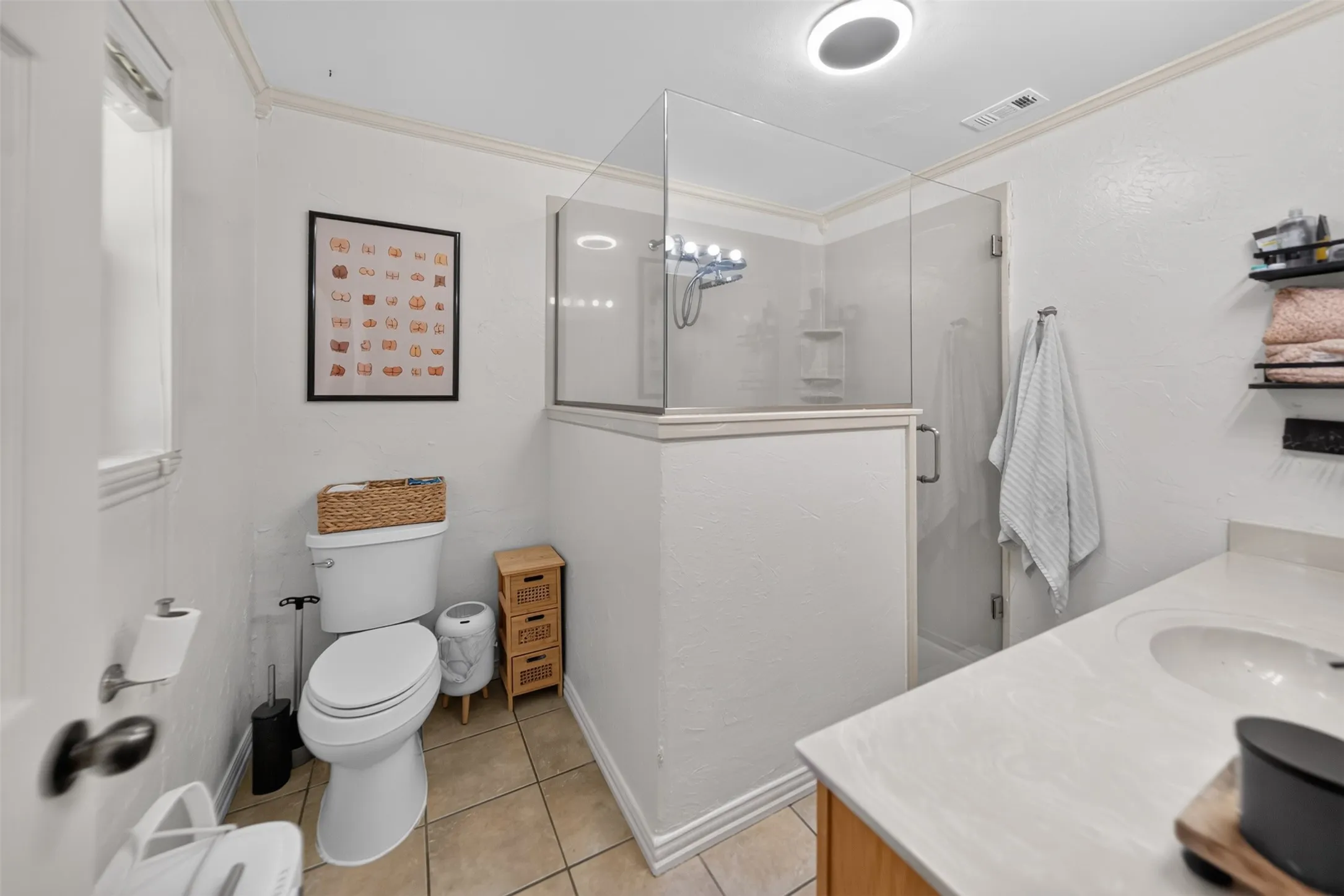 Glass-enclosed shower with a chrome fixture, single vanity with an integrated sink, and tile flooring