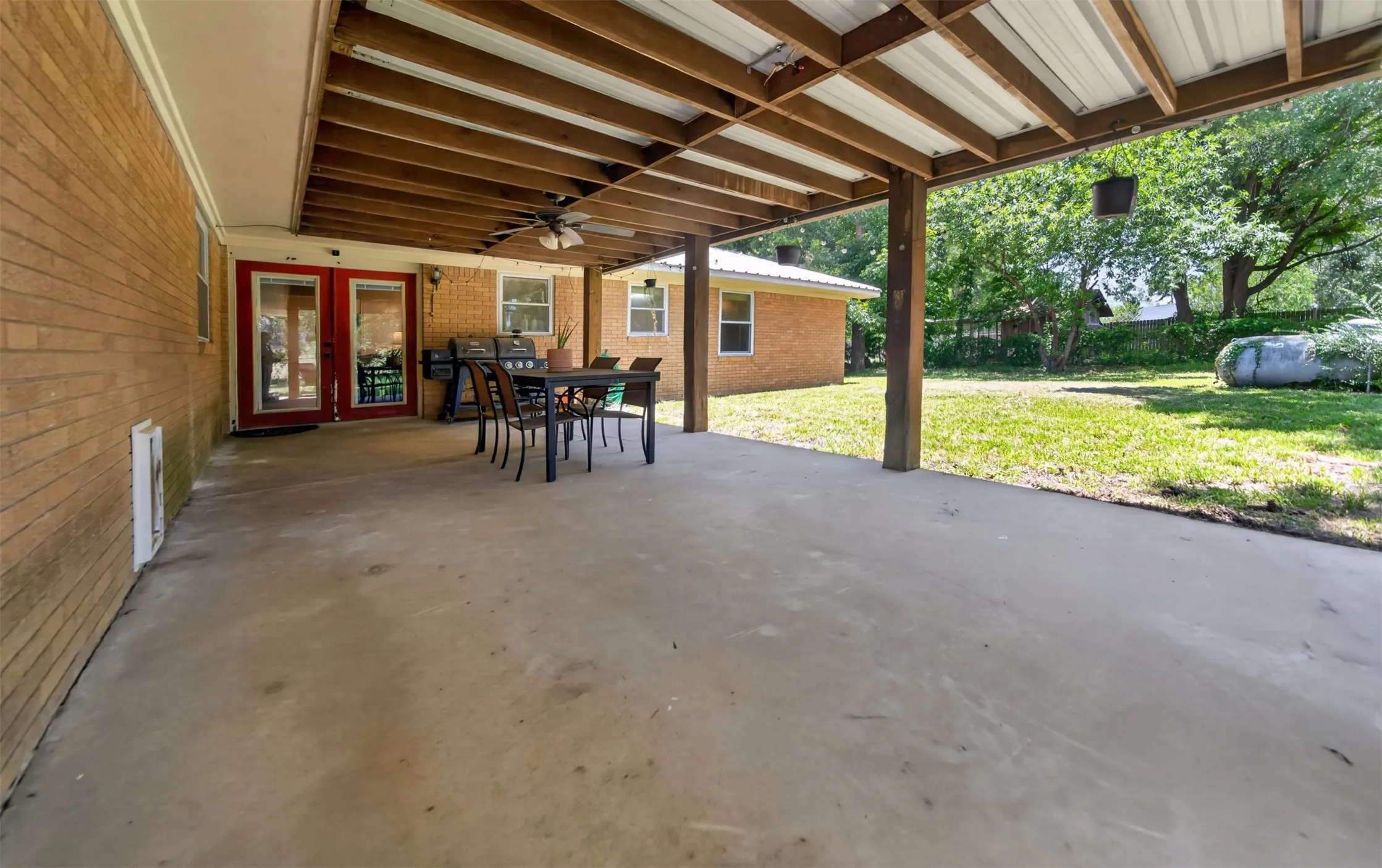 Covered patio with a concrete surface, exposed wood beam ceiling, and a ceiling fan