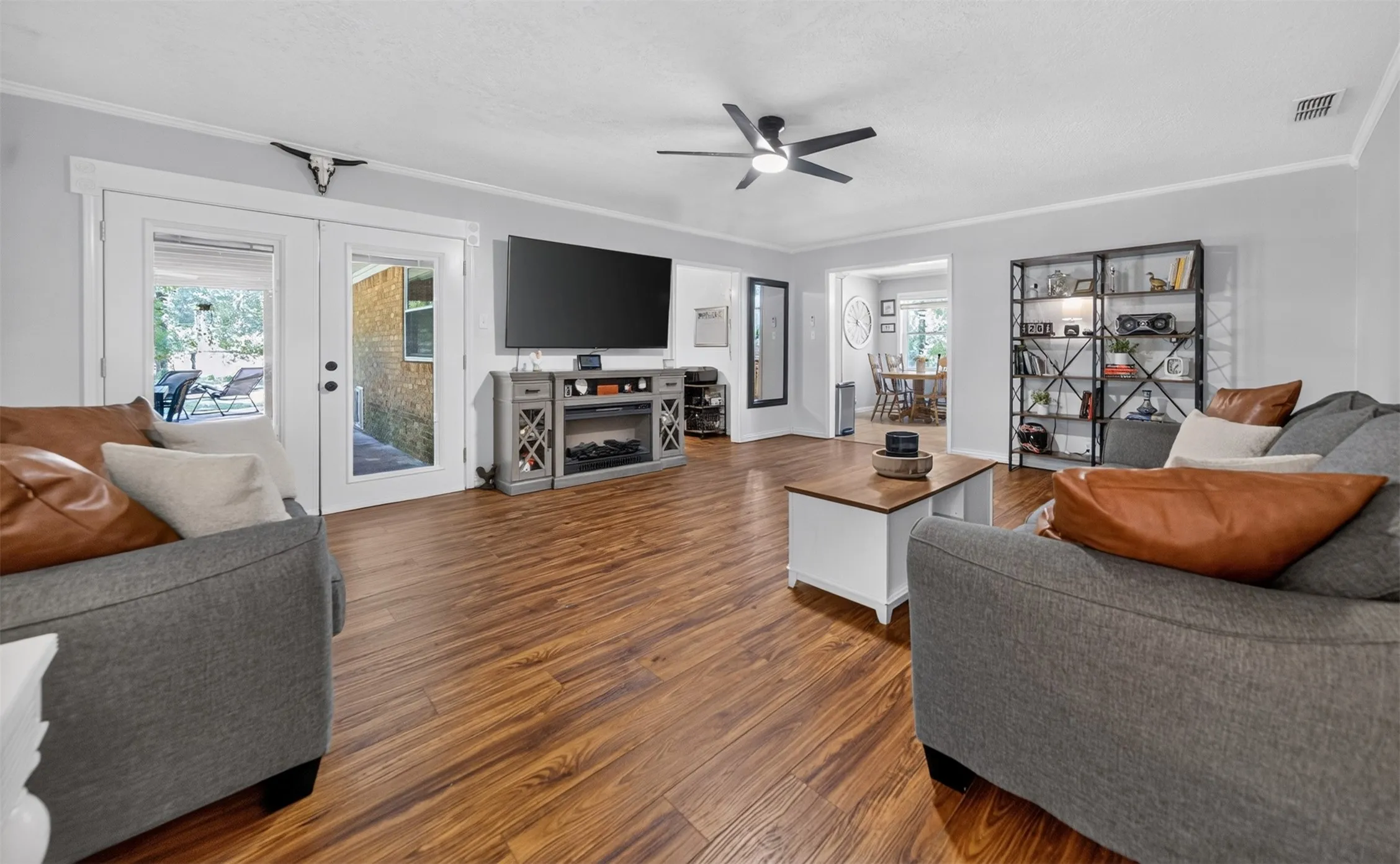 Living area with wood-finish flooring, light grey wall paint, and white crown molding