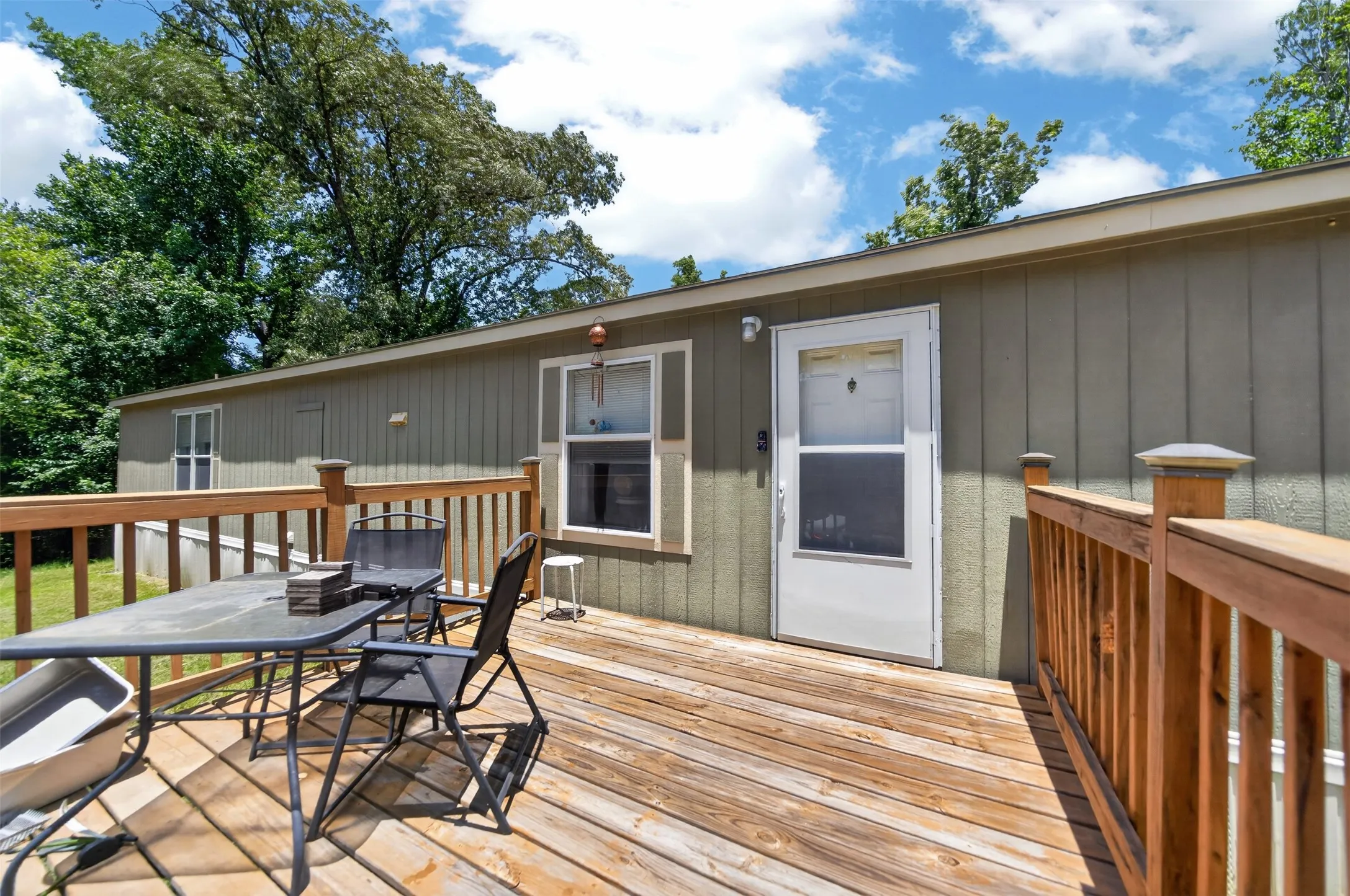 Spacious wood deck with natural wood railings, exterior siding, and a white screen door