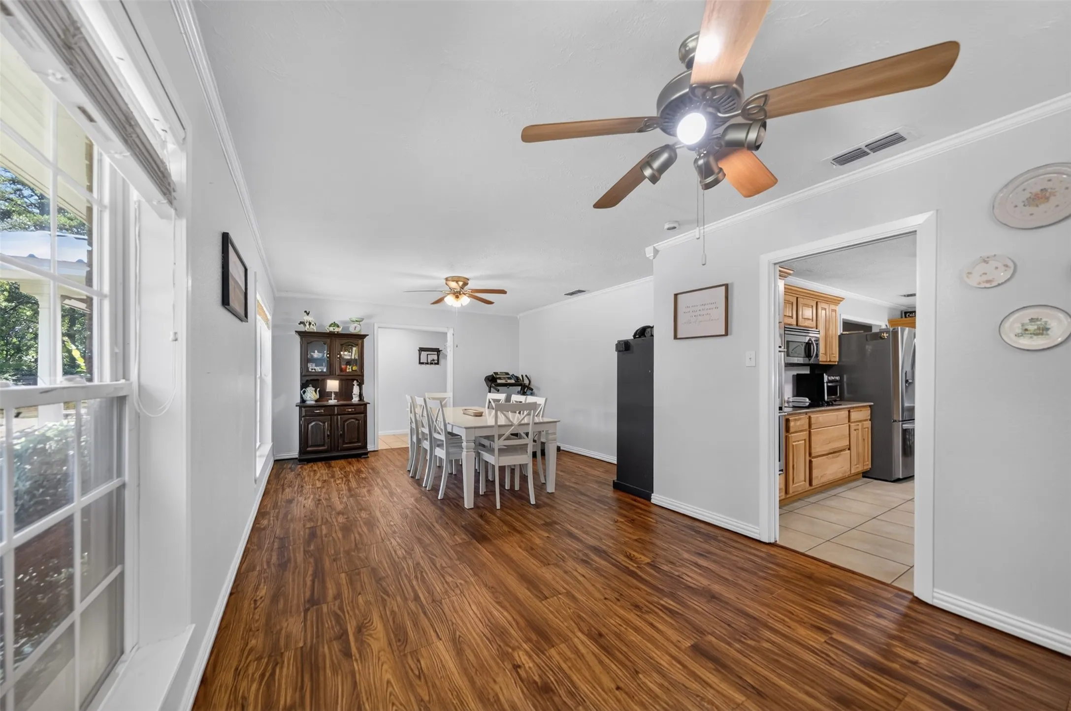 Spacious interior featuring wood-finish flooring, white trim, and a ceiling fan with integrated lighting
