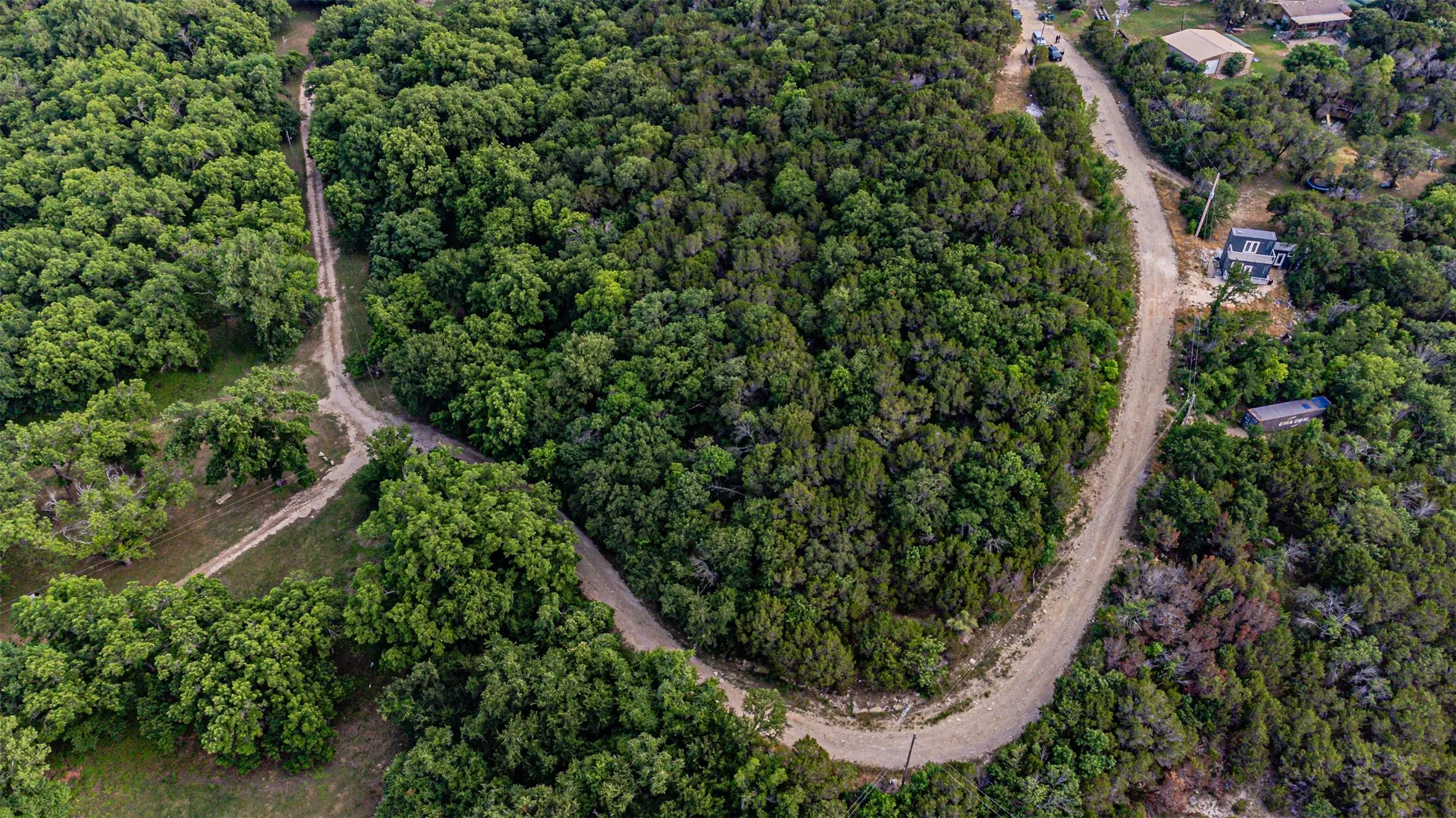Expansive tree-covered acreage with winding dirt roads and visible homesites