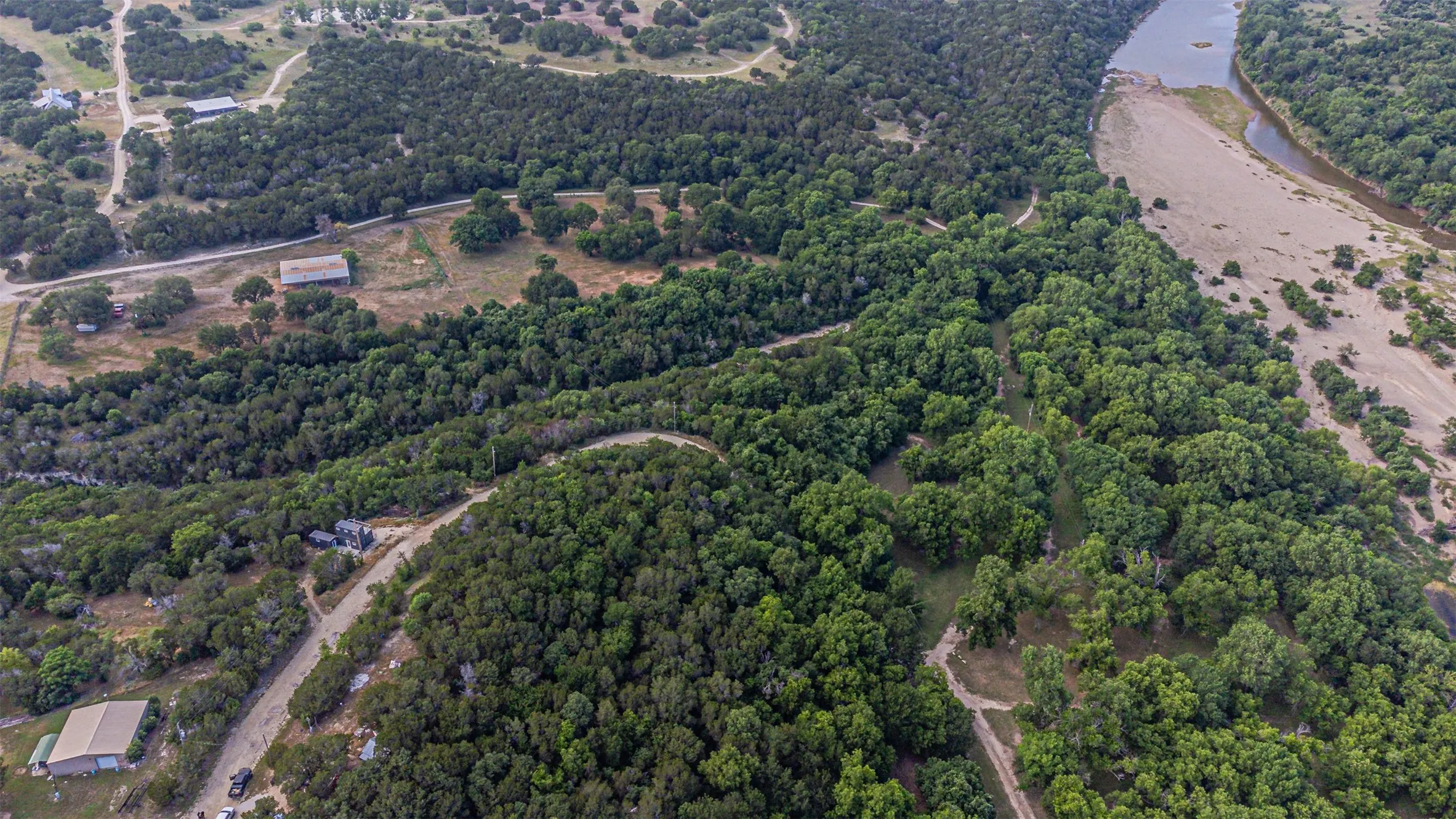 Aerial perspective showcasing a meandering river adjacent to a wooded landscape