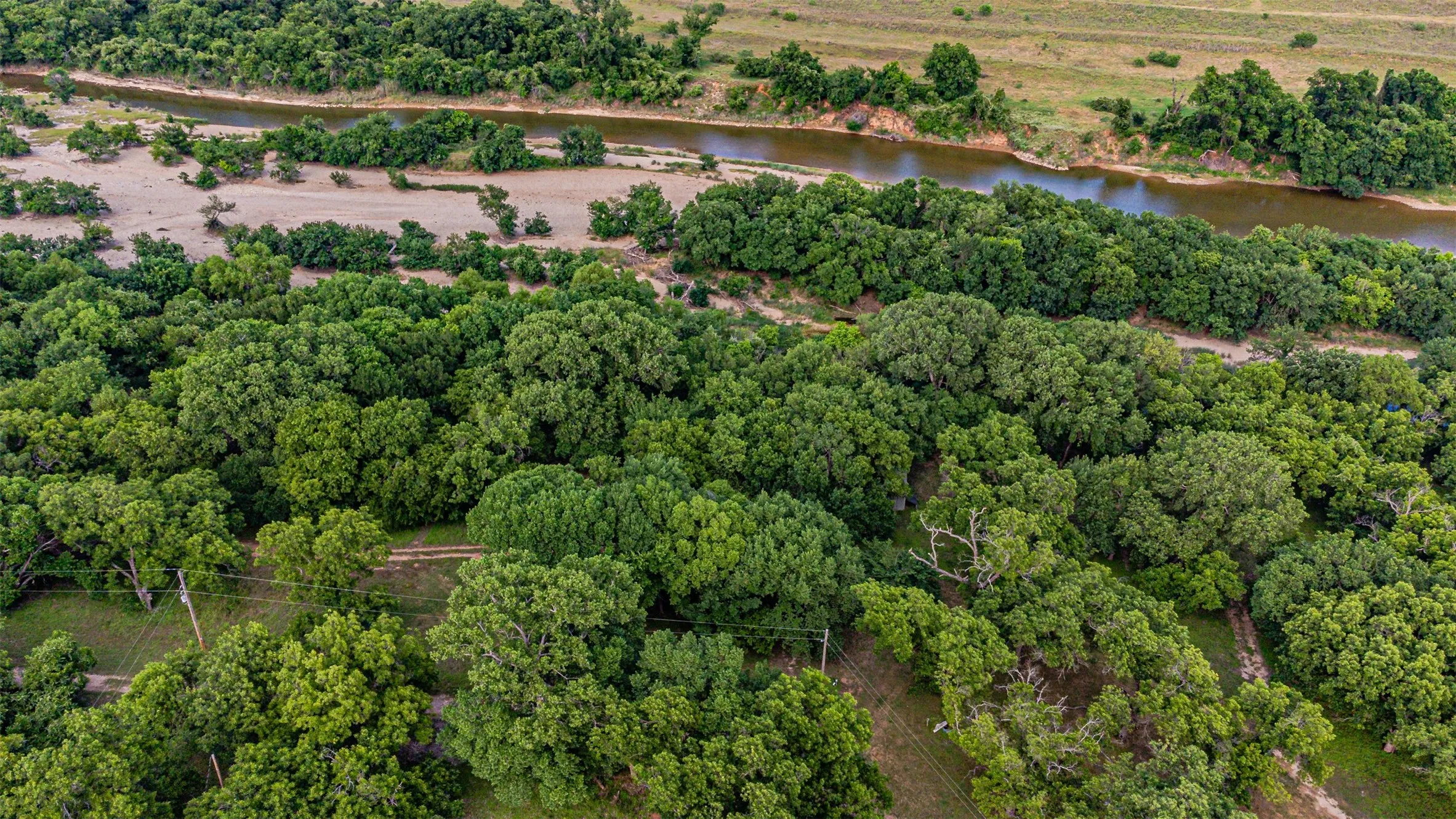 Expansive natural landscape featuring a winding river, dense tree coverage, and a sandy riverbed