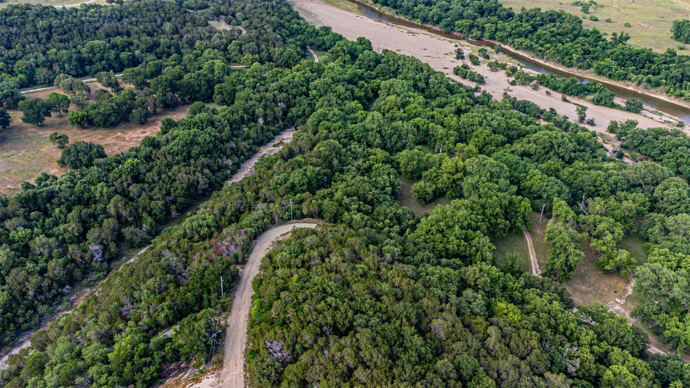 Expansive acreage featuring dense tree coverage, open clearings, and a river frontage with exposed sandbars
