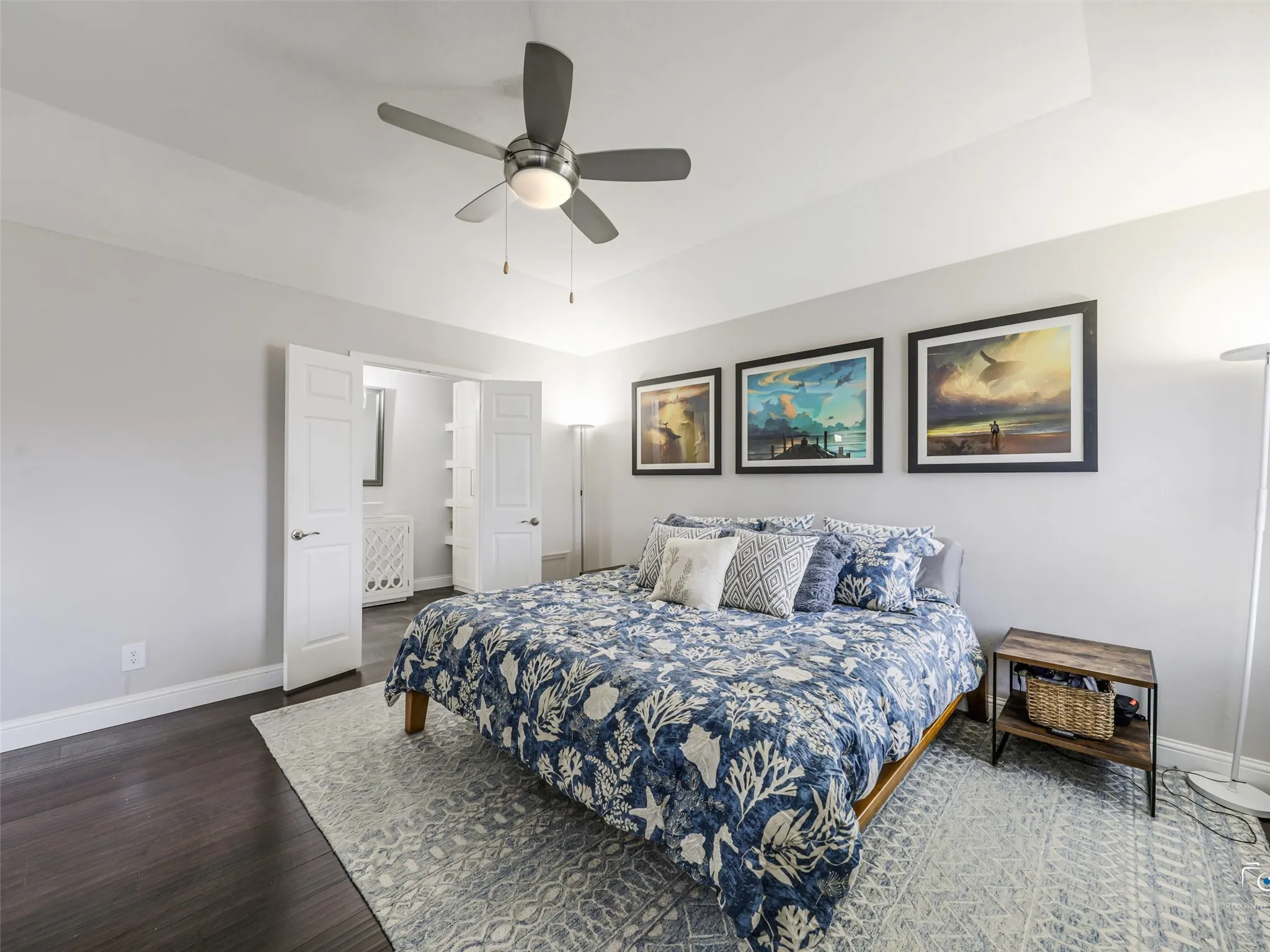 This view of the primary bedroom gives you a peak of the primary bathroom through double doors.