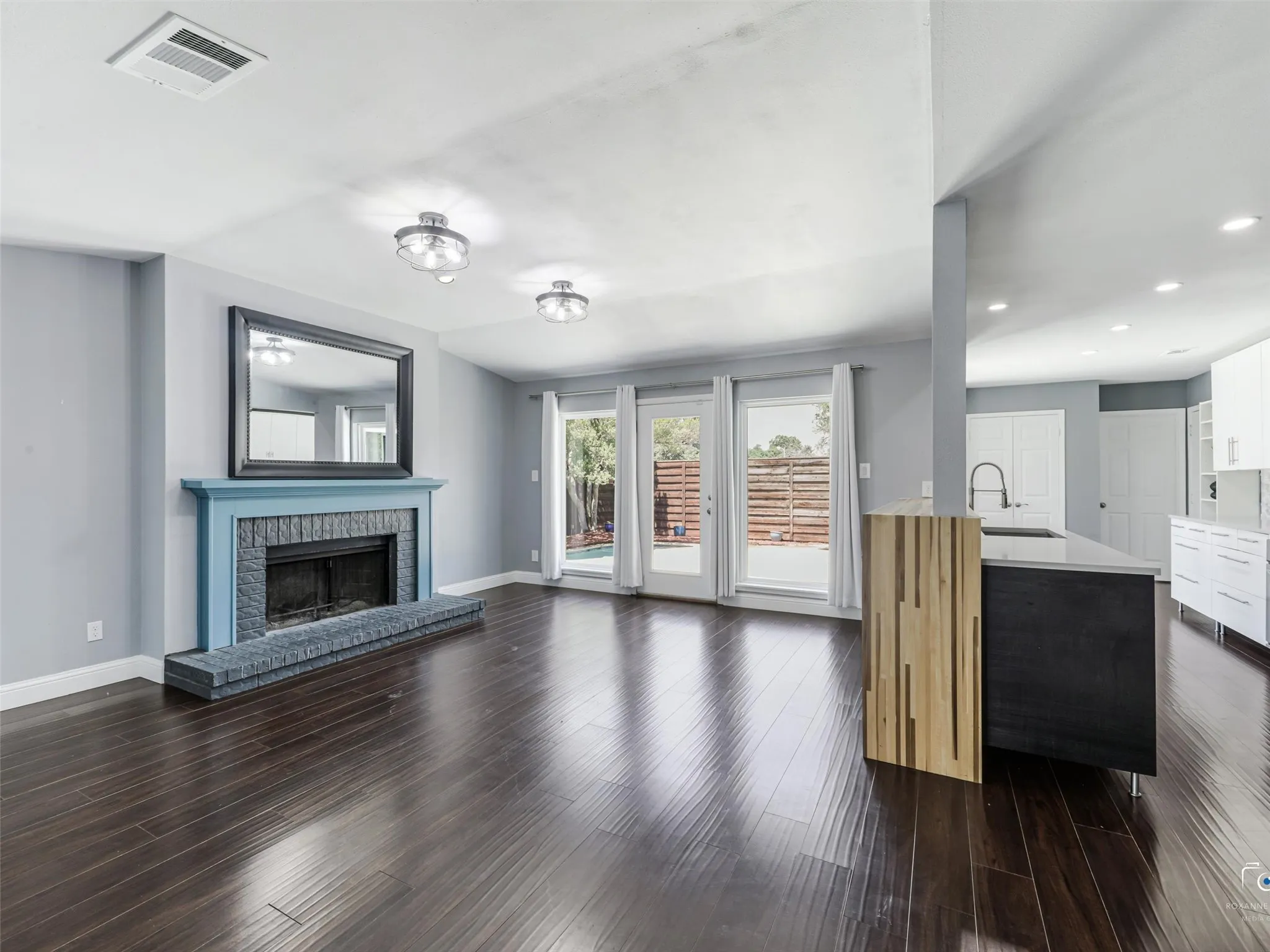 Spacious living area has a lovely fireplace with a hearth and is open to the kitchen and pool-filled backyard.