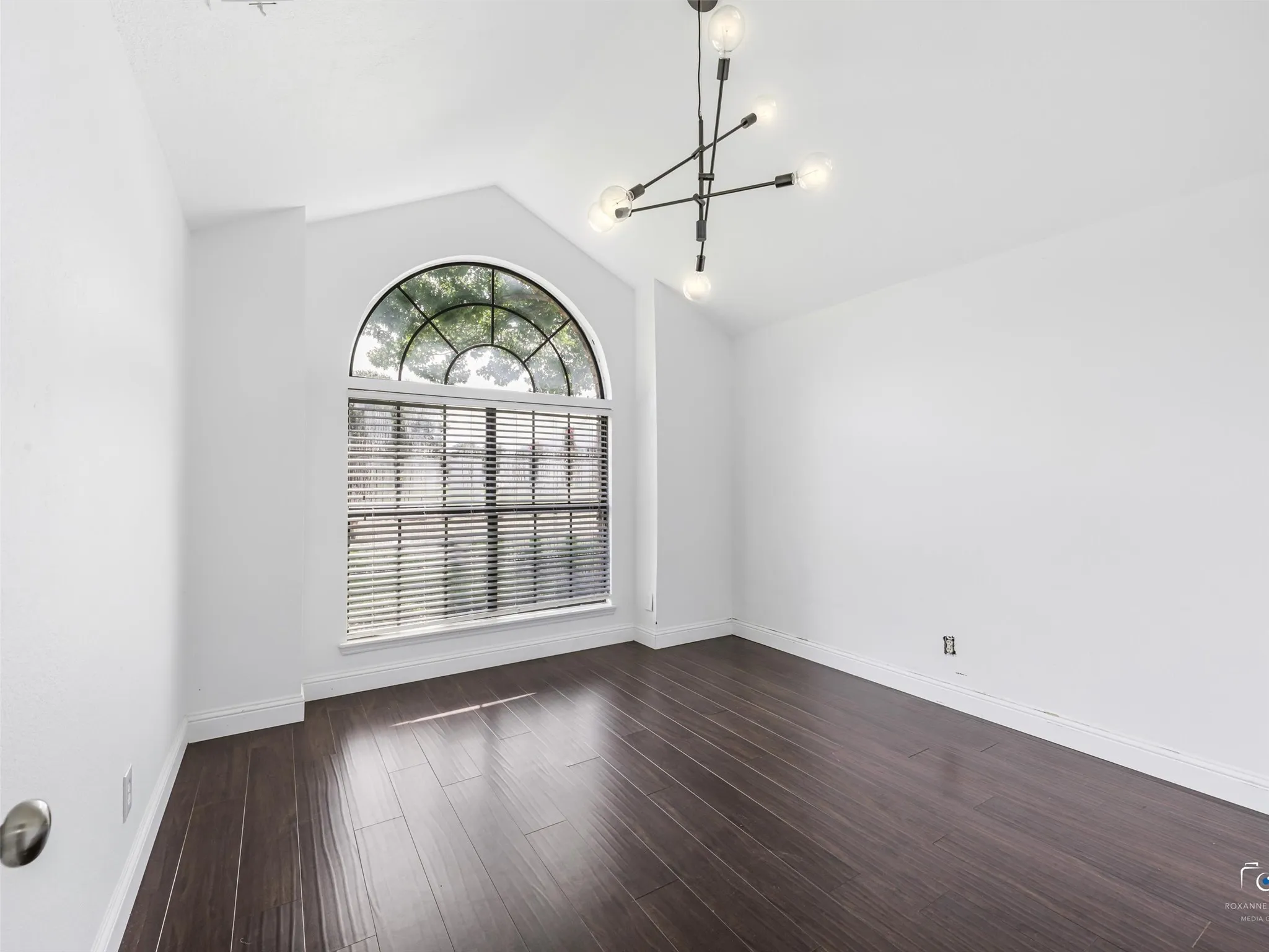 Bedroom three features a vaulted ceiling with an arch-top window, the same wood flooring, and a modern sputnik-style chandelier
