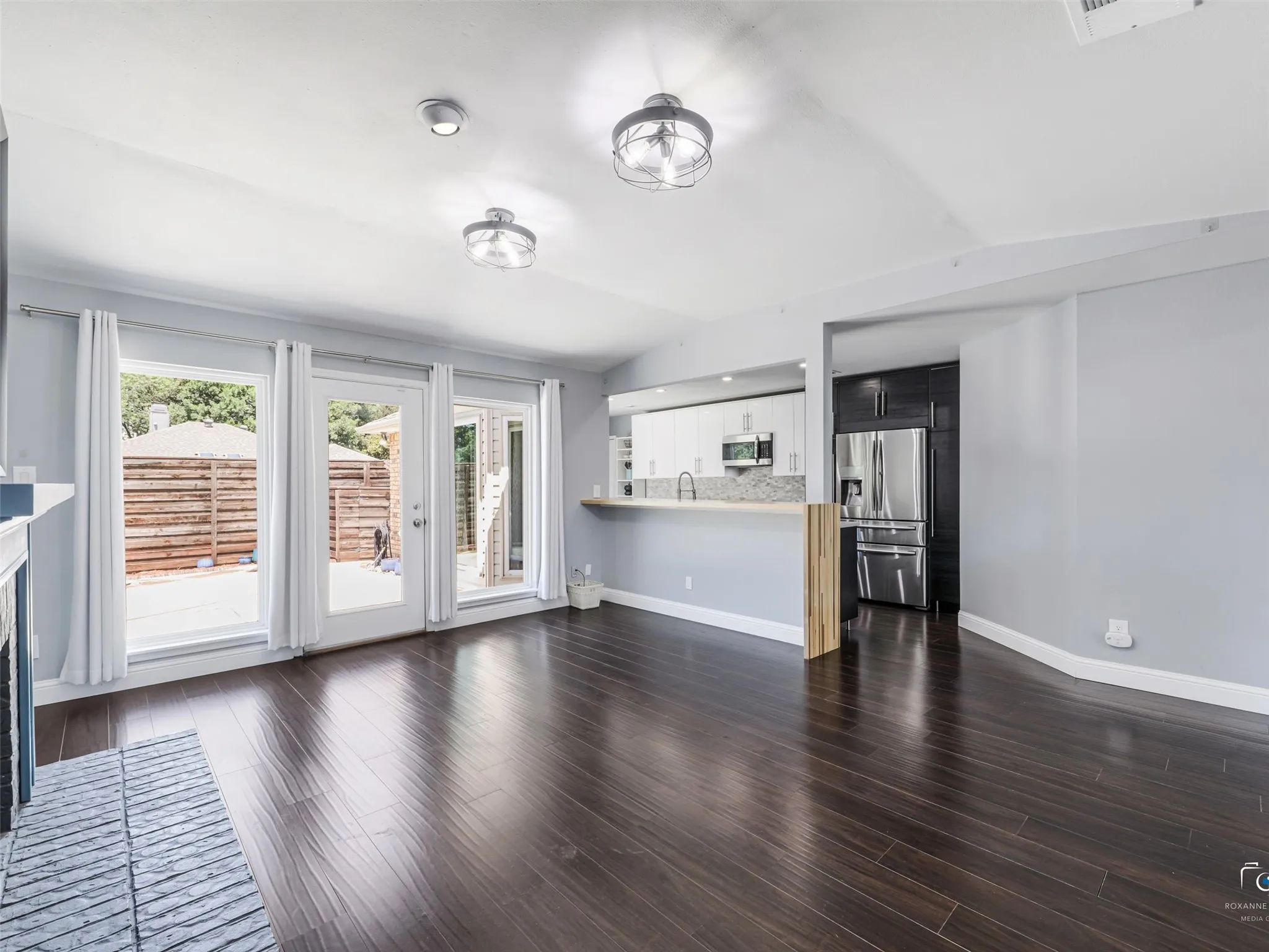 Open-concept living area featuring dark wood-finish flooring opens to the updated kitchen. Note that board on board fence in the backyard!