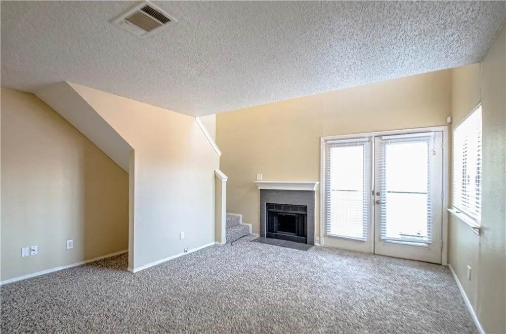 Living area featuring a fireplace with a grey surround and white mantel, light-toned walls, and grey carpeting