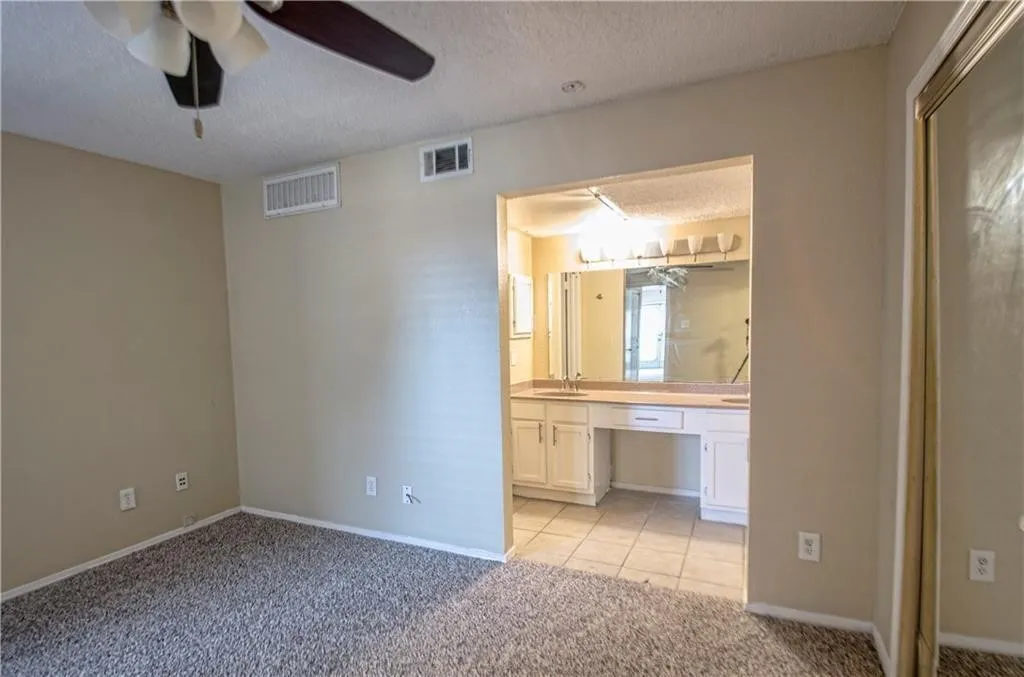 Bedroom with soft carpeting, ceiling fan, and direct access to a vanity area