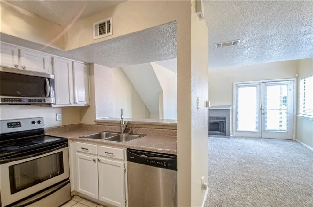 Kitchen with white cabinetry, stainless steel appliances, and a double basin sink