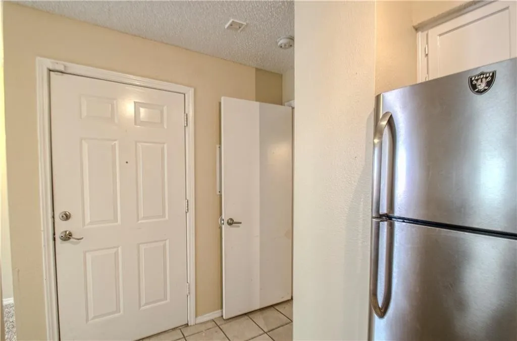 Entryway featuring a six-panel door with brushed nickel hardware, neutral wall paint, and a textured ceiling