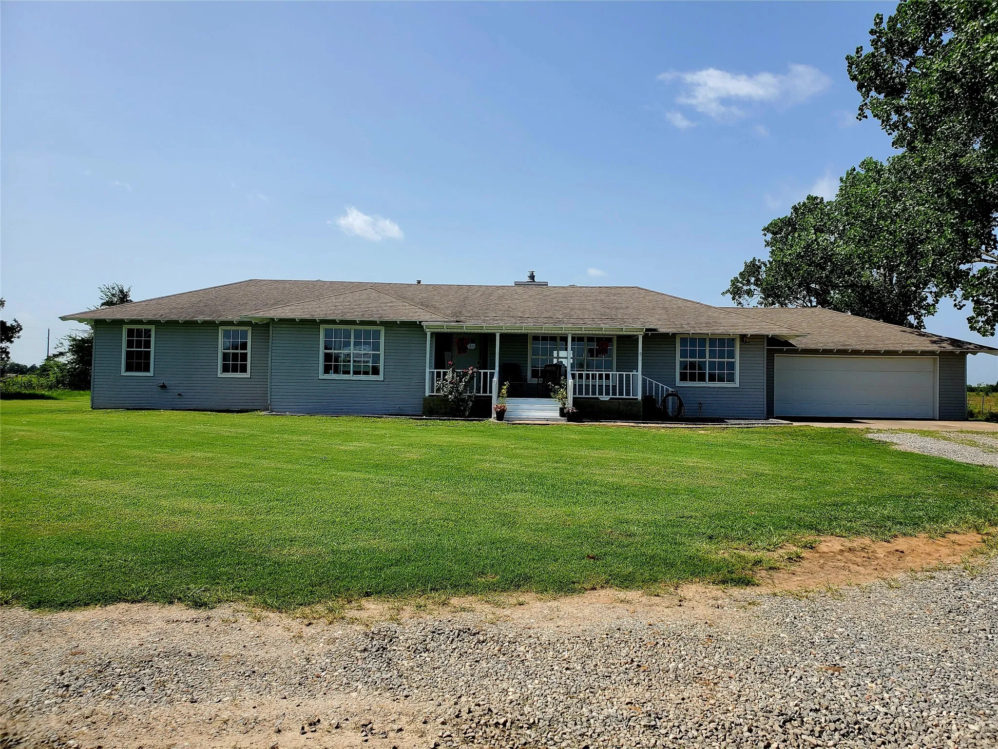 Ranch-style residence featuring a light gray exterior, white trim, and a covered front porch with white railings