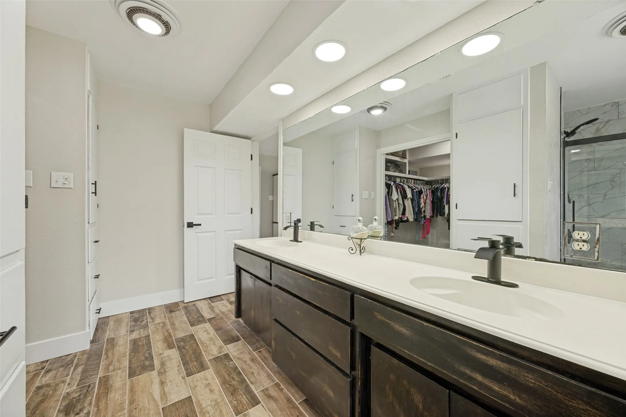 Bathroom featuring a dual vanity with dark wood cabinetry, white countertops, and black fixtures