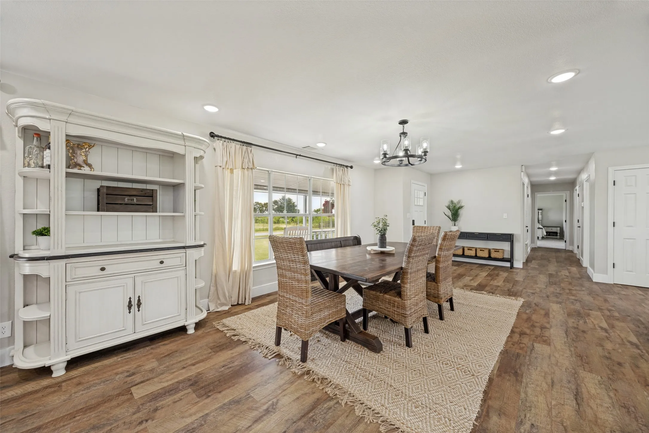 Bright dining area featuring wood-finish flooring, a large window, a built-in hutch, recessed lighting, and a dark metal chandelier