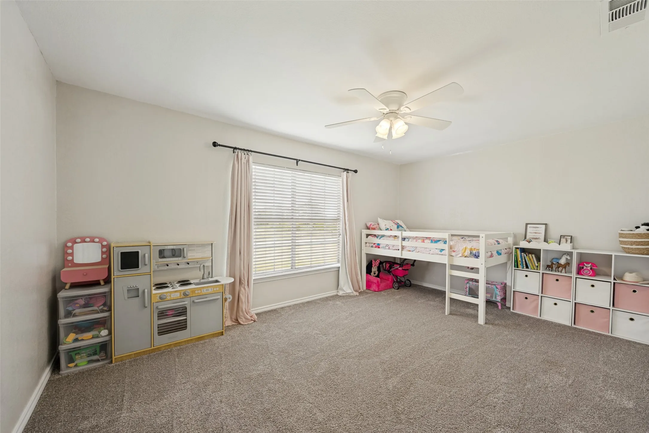 Carpeted room featuring a ceiling fan, a window with blinds and drapes, and neutral wall paint
