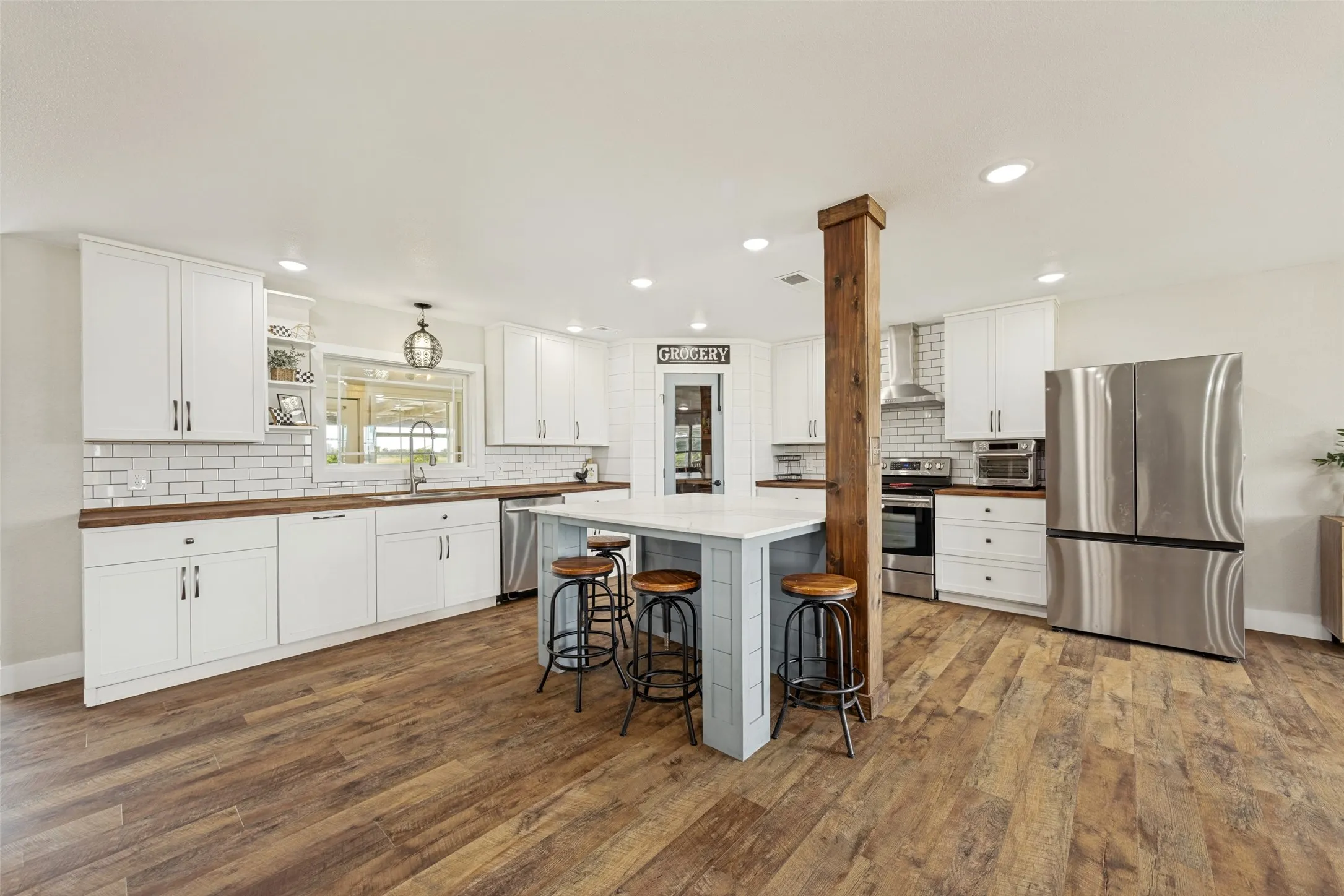 Kitchen featuring wood-finish flooring, white cabinetry, wood countertops, and a subway tile backsplash