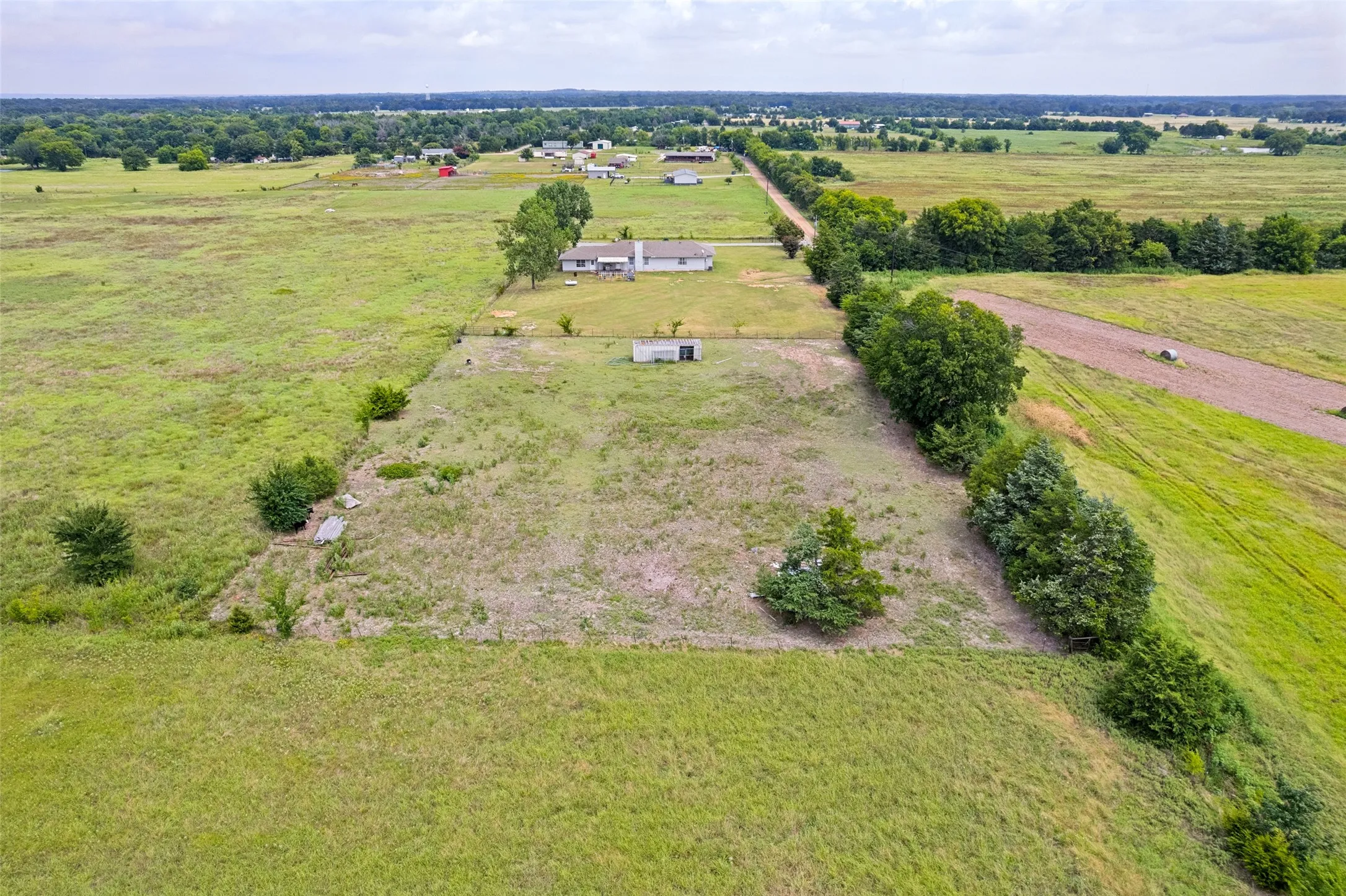 Expansive rural property featuring an established residence, a secondary outbuilding, and a gravel road access point
