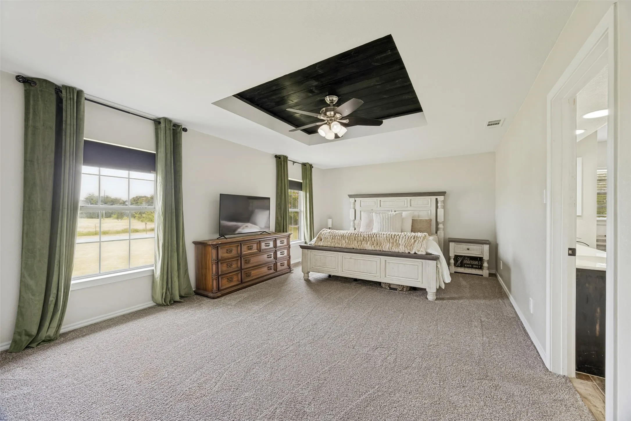 Spacious room featuring a recessed ceiling with a dark wood-finish accent and a ceiling fan