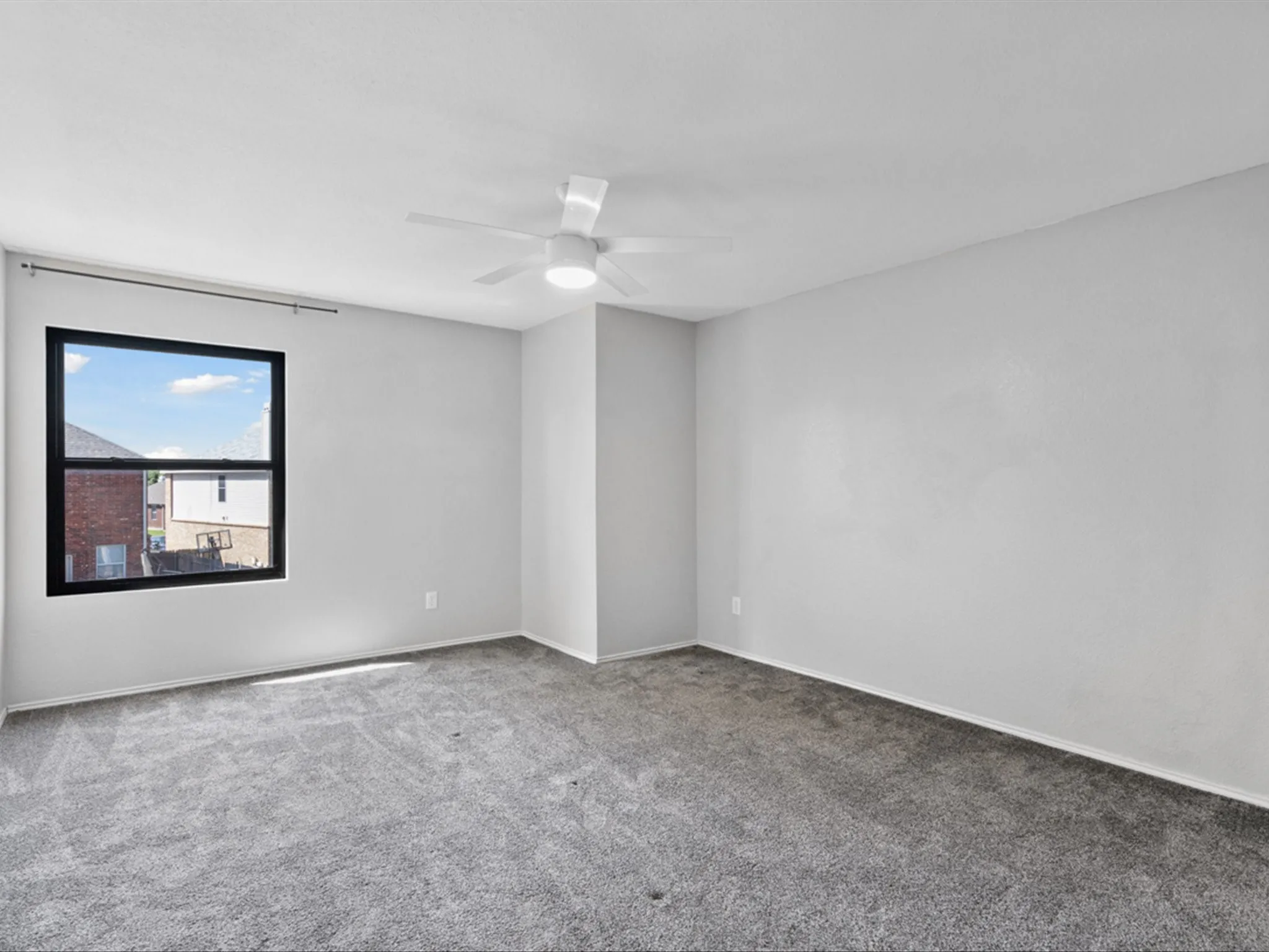 Carpeted empty room with a ceiling fan and baseboards
