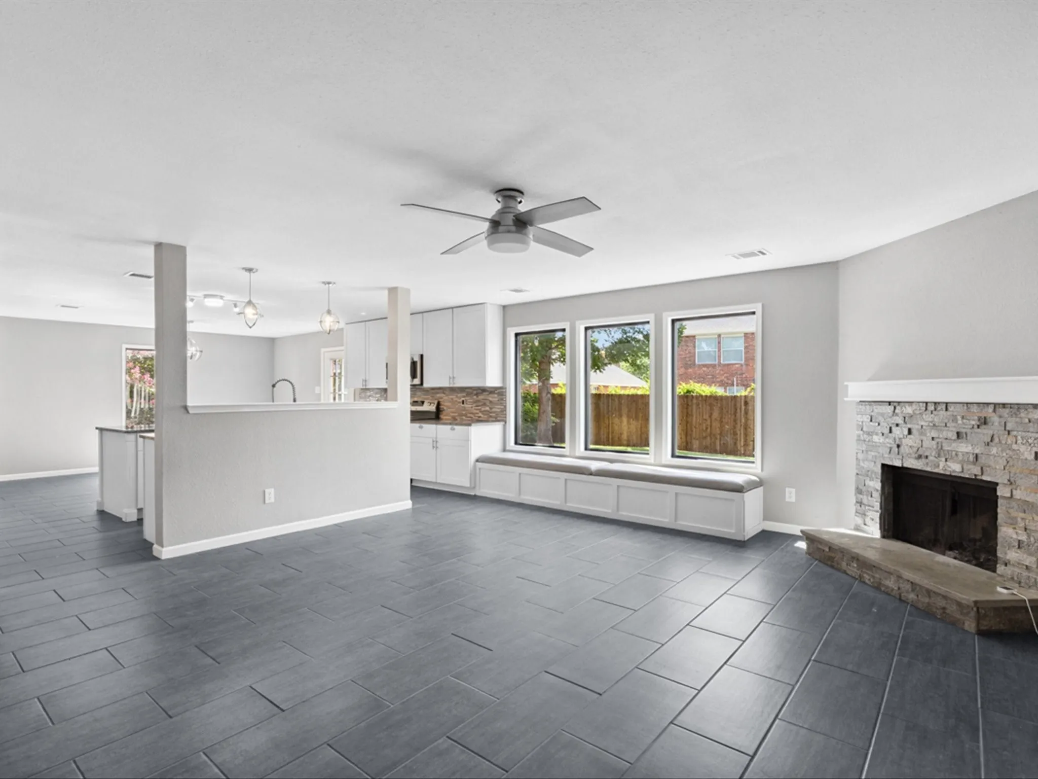 Unfurnished living room featuring ceiling fan and a stone fireplace