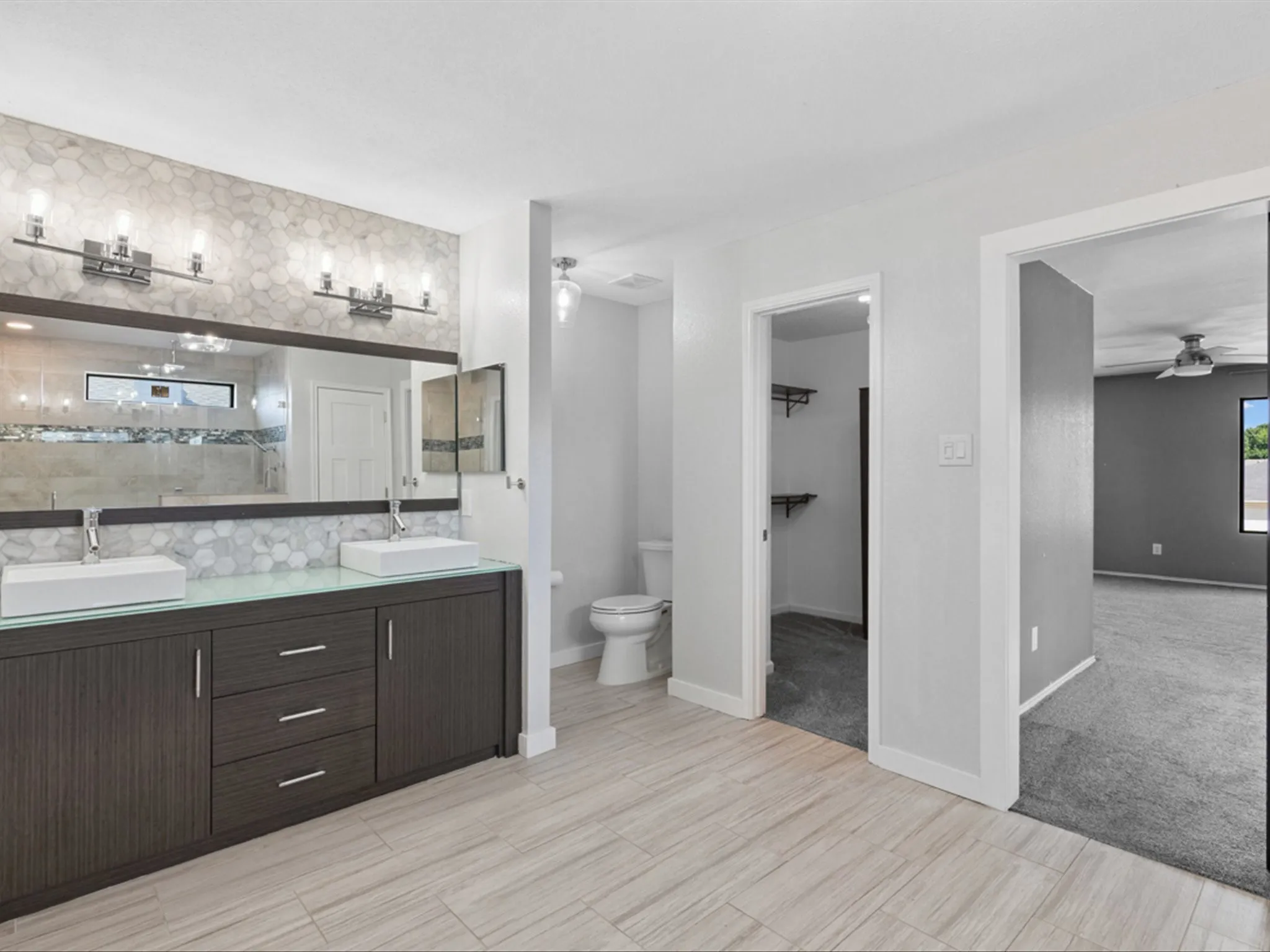 Full bath with double vanity, ceiling fan, and tiled shower