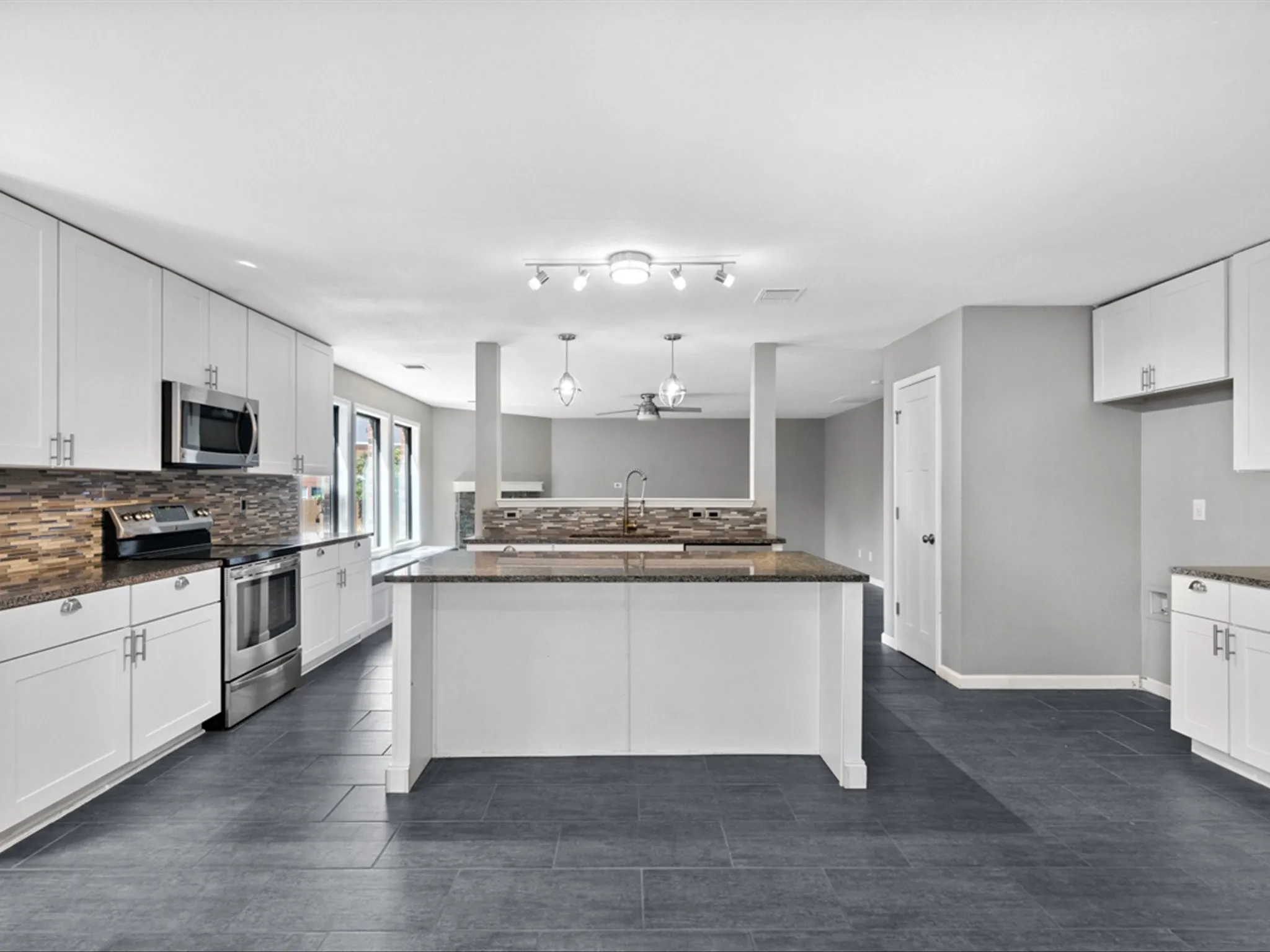 Kitchen featuring stainless steel appliances, ceiling fan, tasteful backsplash, and white cabinetry