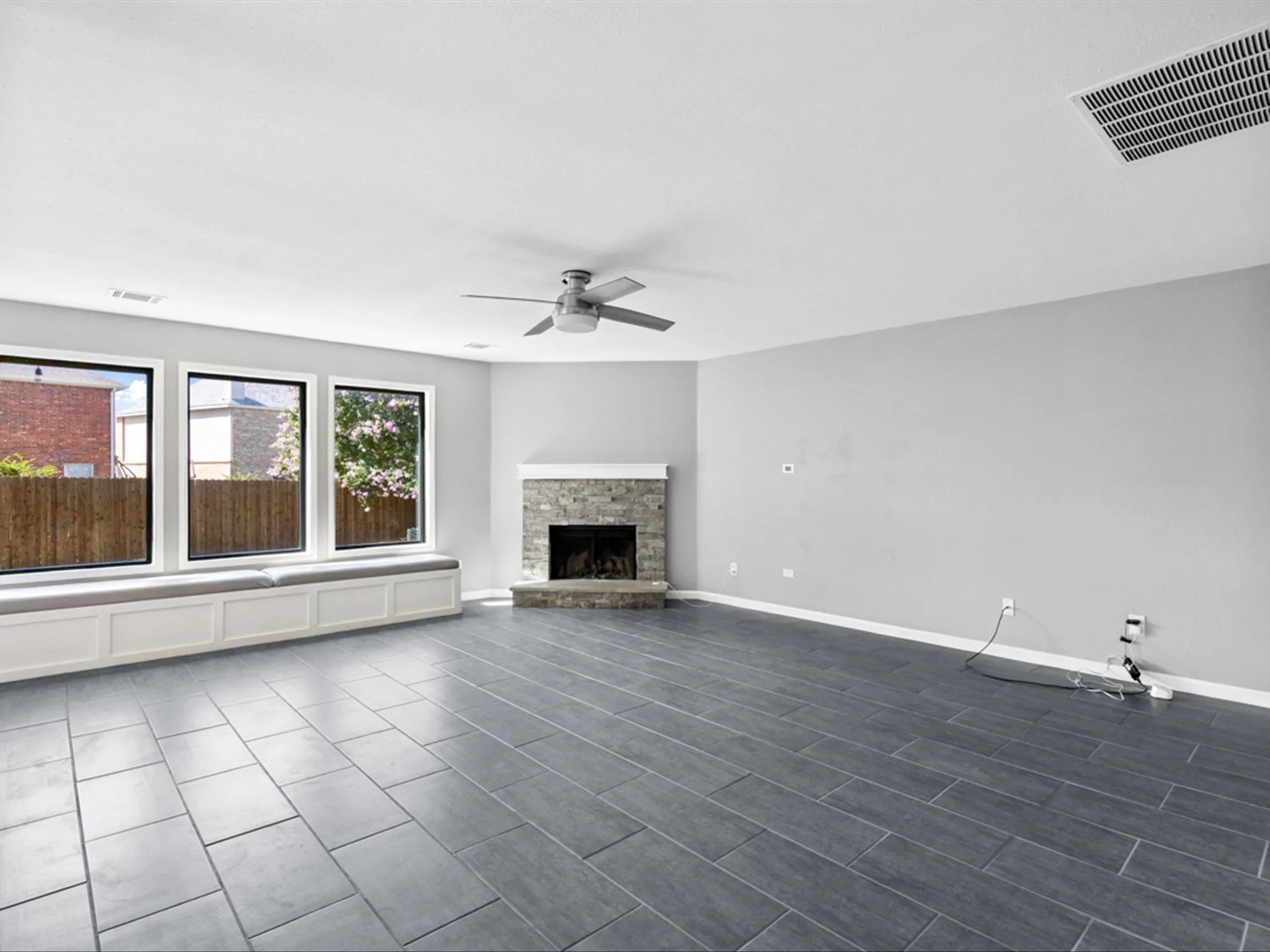 Unfurnished living room with ceiling fan and a stone fireplace
