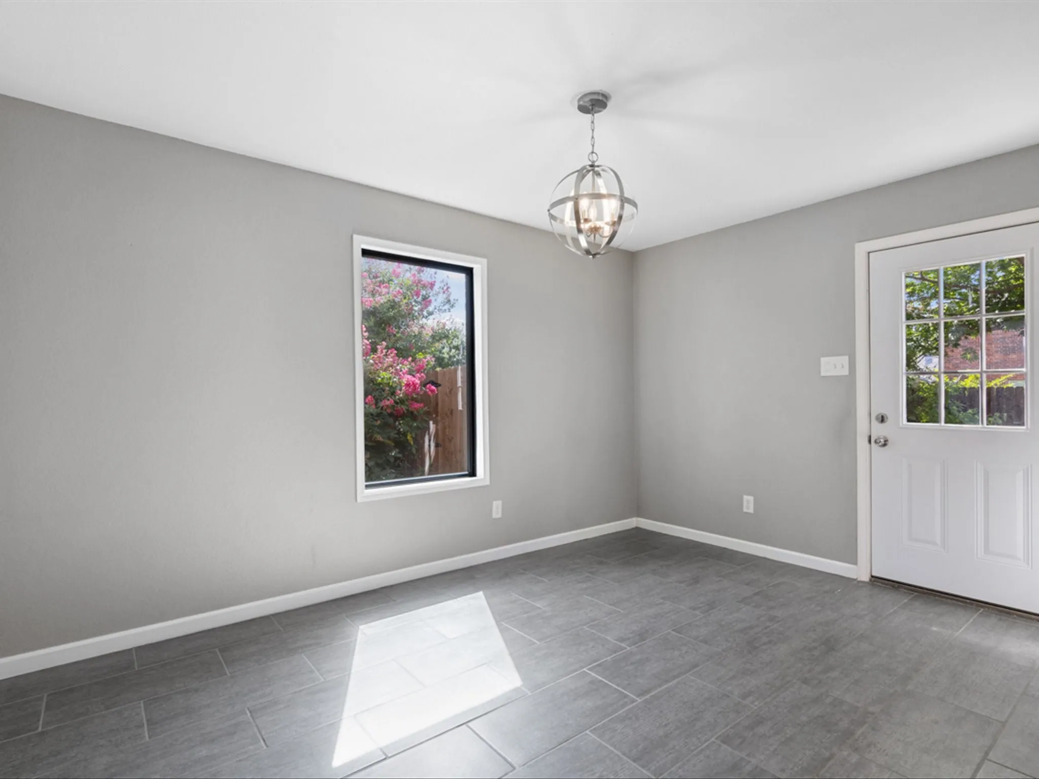 Spare room featuring a chandelier and baseboards
