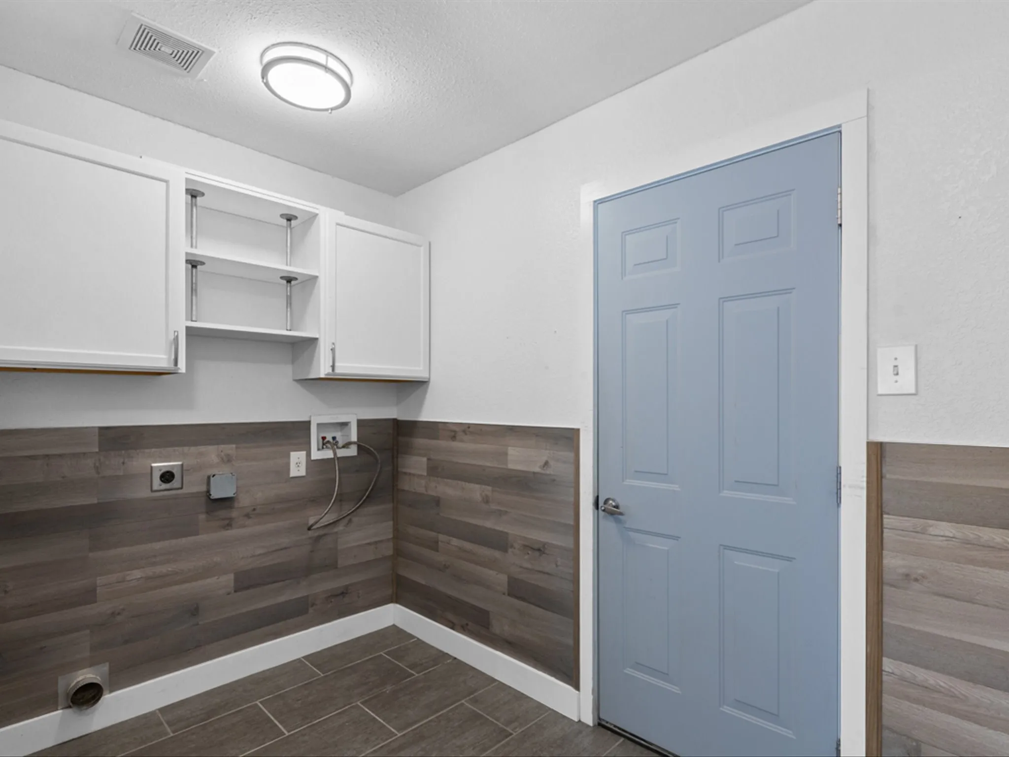 Washroom with cabinet space, electric dryer hookup, washer hookup, wainscoting, and a textured ceiling