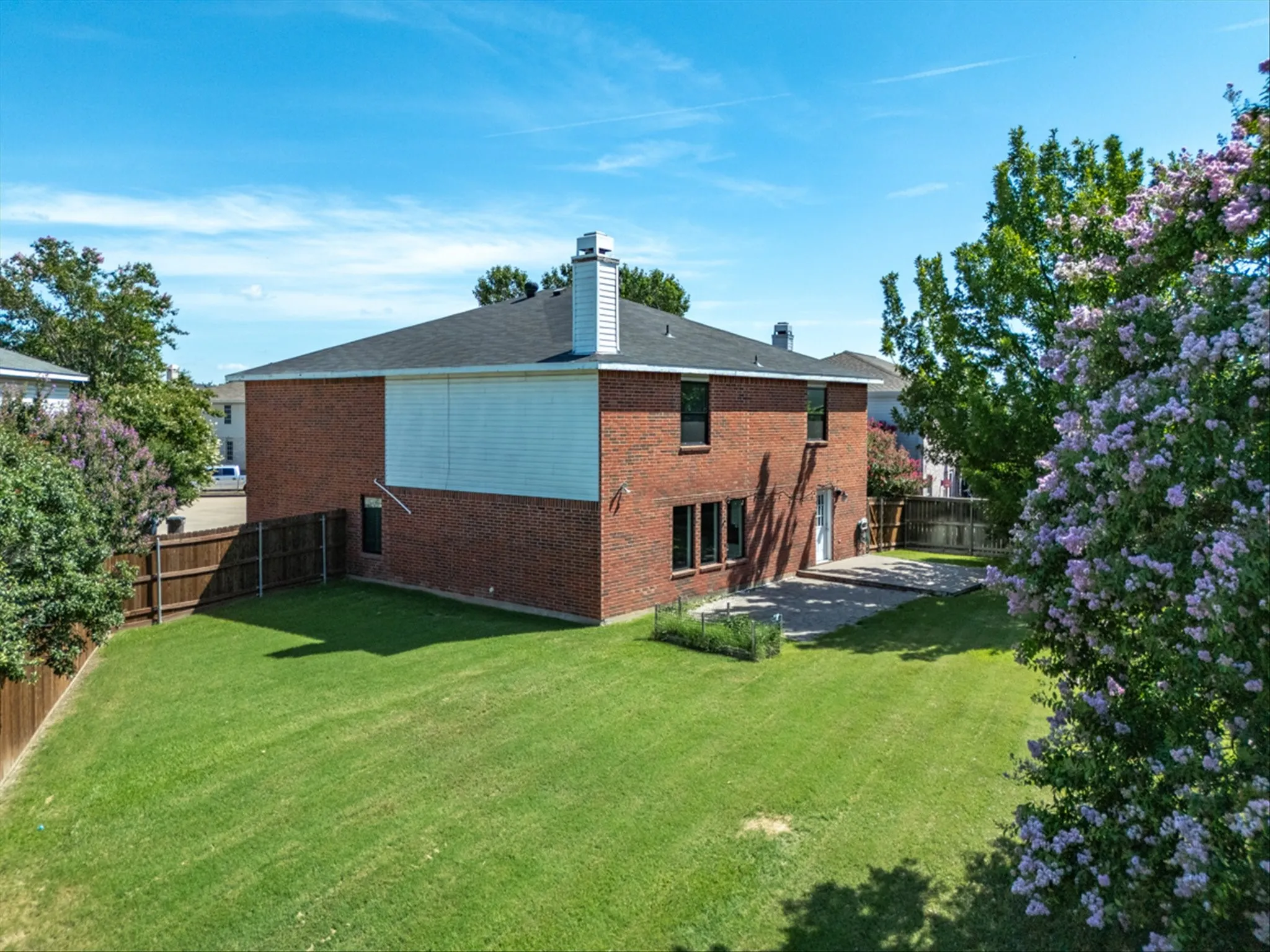 Back of house featuring brick siding, a fenced backyard, a patio, and a chimney