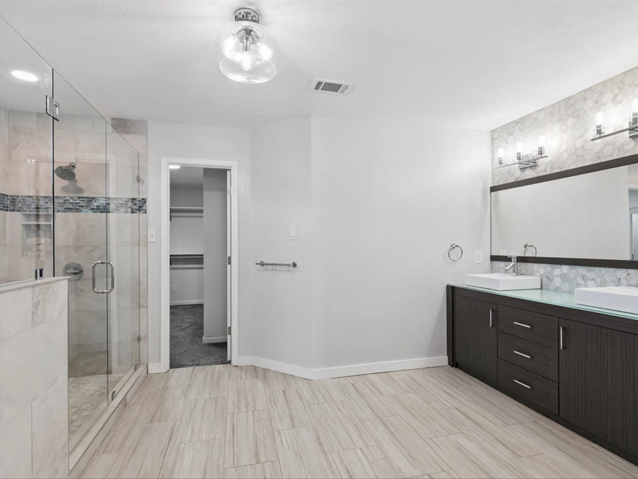 Full bathroom featuring double vanity, a stall shower, and a walk in closet
