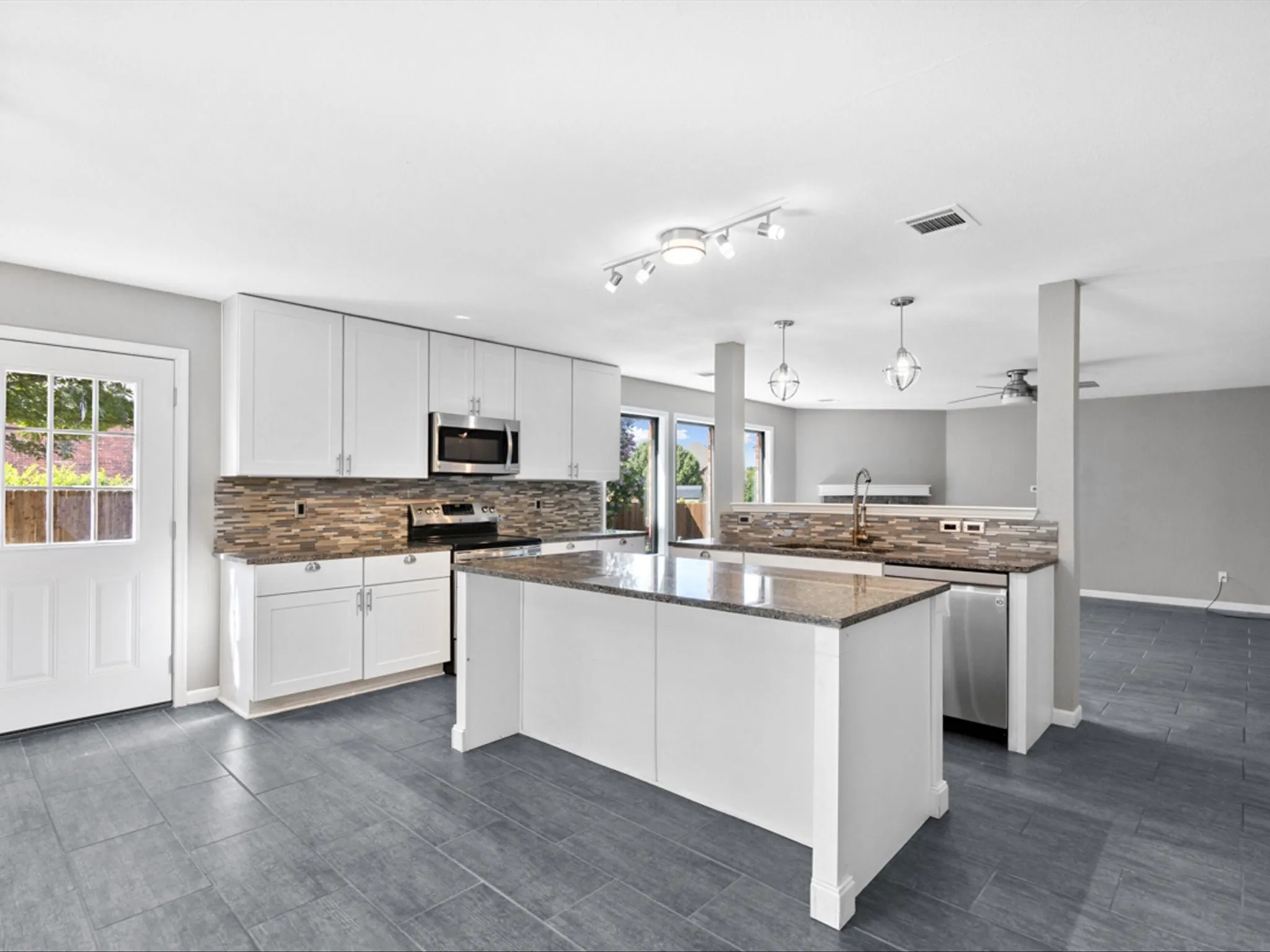 Kitchen with appliances with stainless steel finishes, tasteful backsplash, white cabinets, a center island, and a peninsula