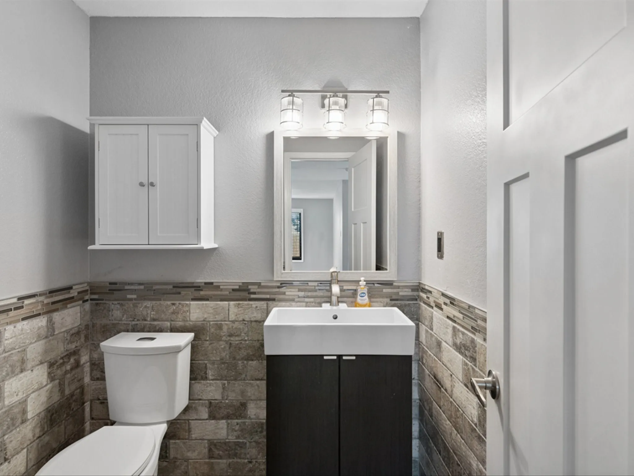Half bath with tile walls, vanity, and a wainscoted wall
