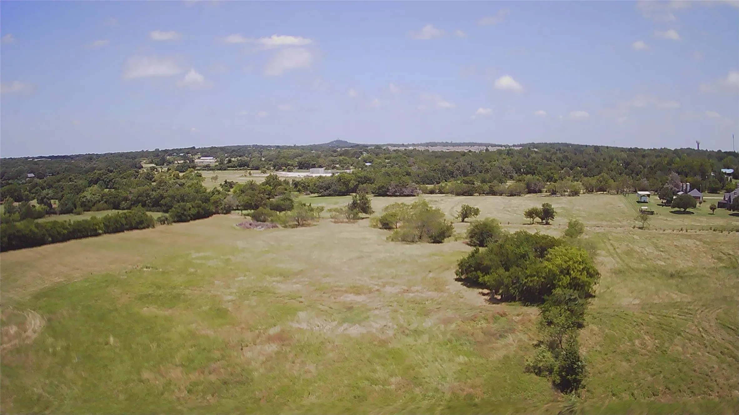 Expansive open land featuring diverse vegetation and mature trees