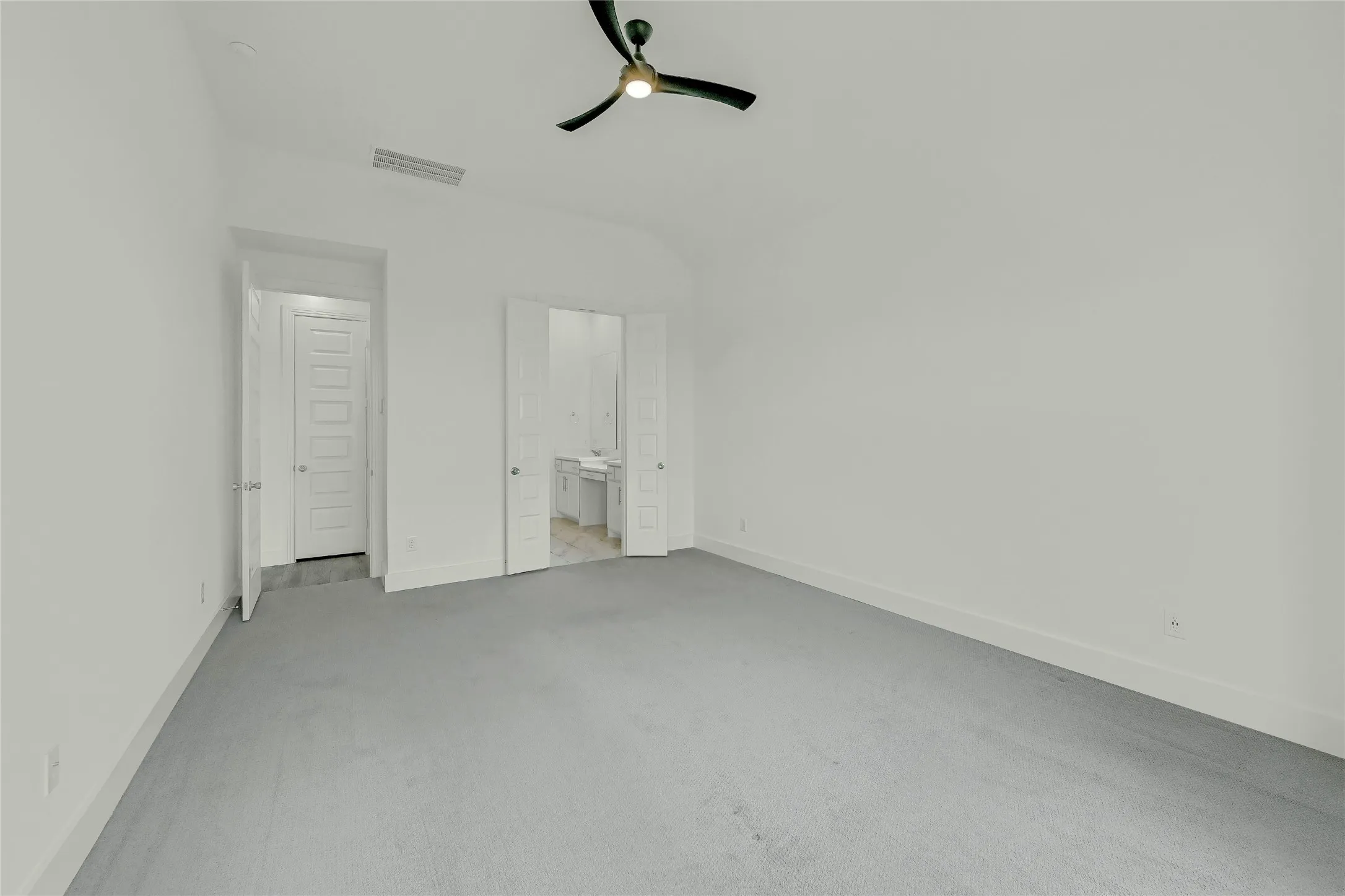 Unfurnished bedroom with carpet floors, visible vents, baseboards, ceiling fan, and ensuite bath